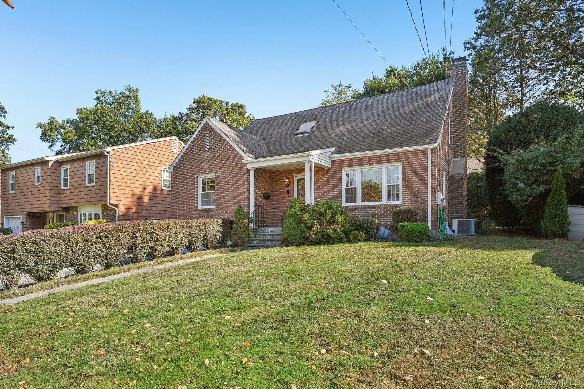 View of front of house featuring a chimney, covered porch, a front lawn, and brick siding View of front of house featuring a chimney, covered porch, a front lawn, and brick siding