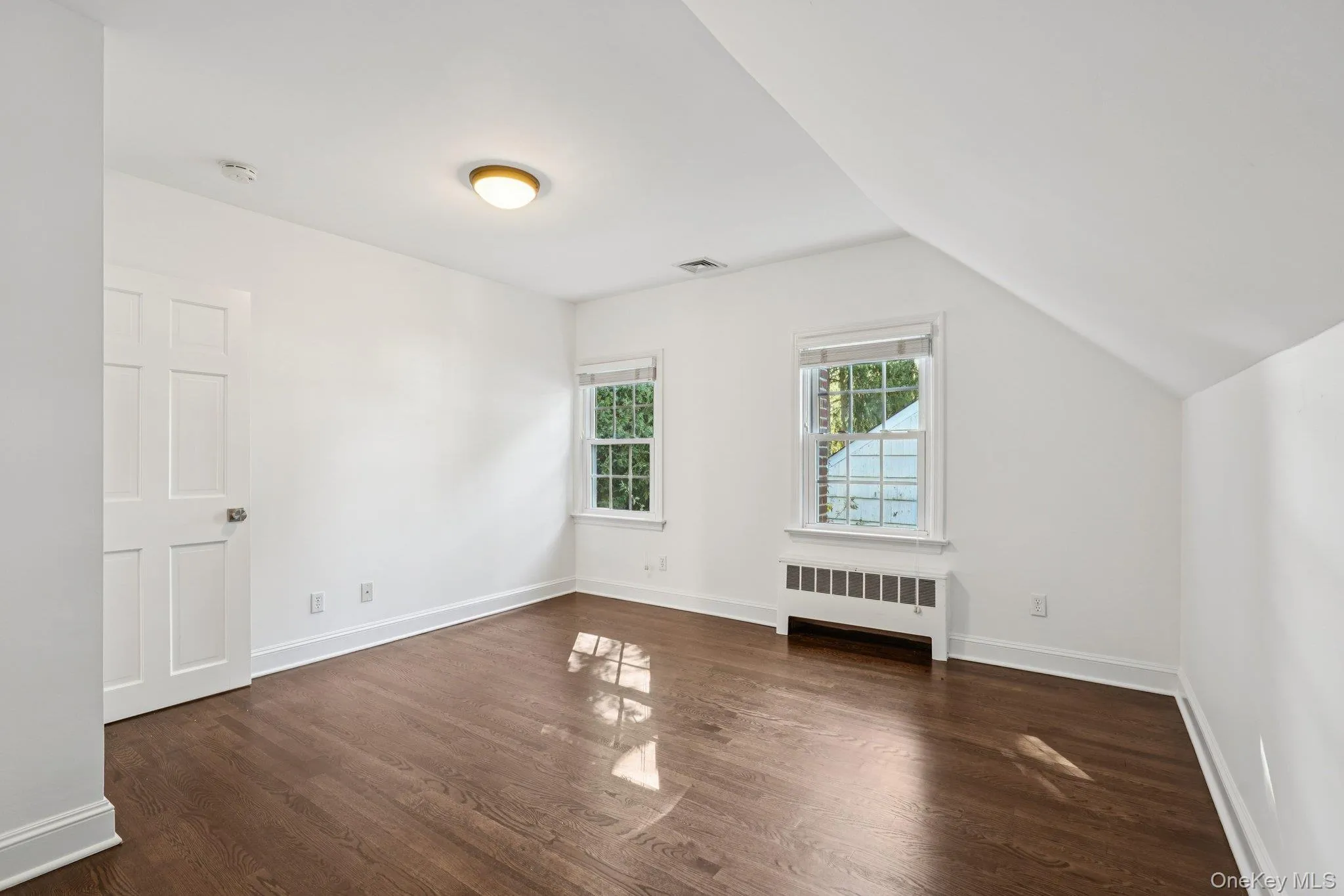Bonus room with radiator, dark wood-type flooring, and vaulted ceiling Bonus room with radiator, dark wood-type flooring, and vaulted ceiling