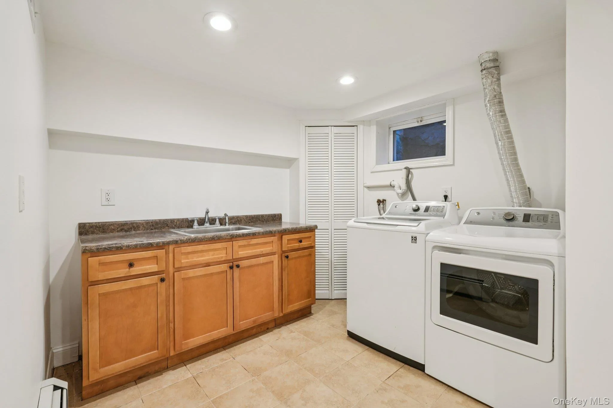 Washroom featuring recessed lighting, separate washer and dryer, light tile patterned flooring, and cabinet space Washroom featuring recessed lighting, separate washer and dryer, light tile patterned flooring, and cabinet space