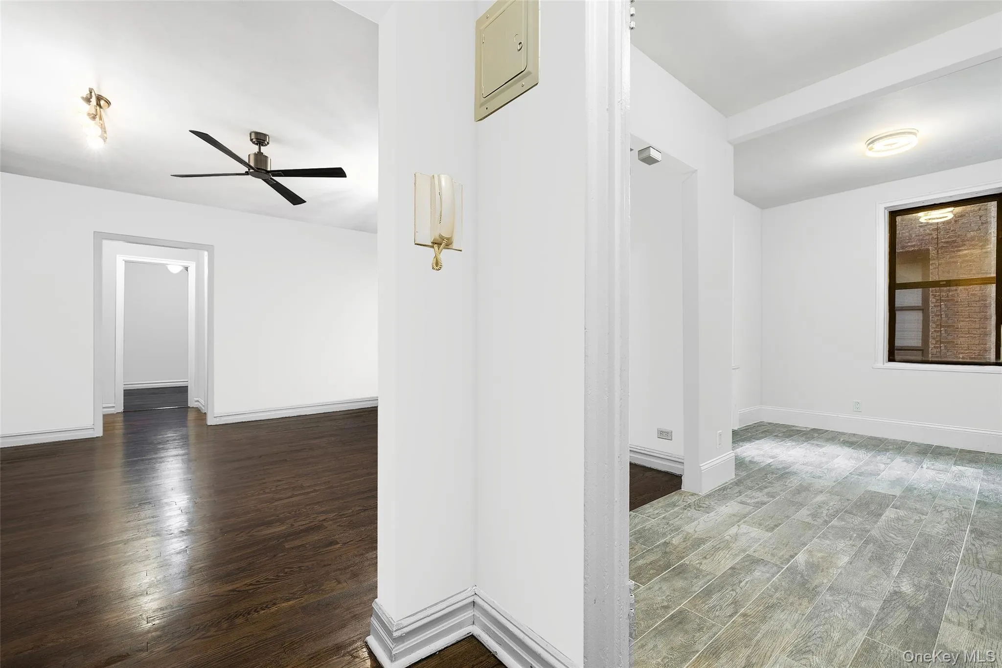 Empty room featuring dark wood-type flooring, a ceiling fan, and electric panel Empty room featuring dark wood-type flooring, a ceiling fan, and electric panel