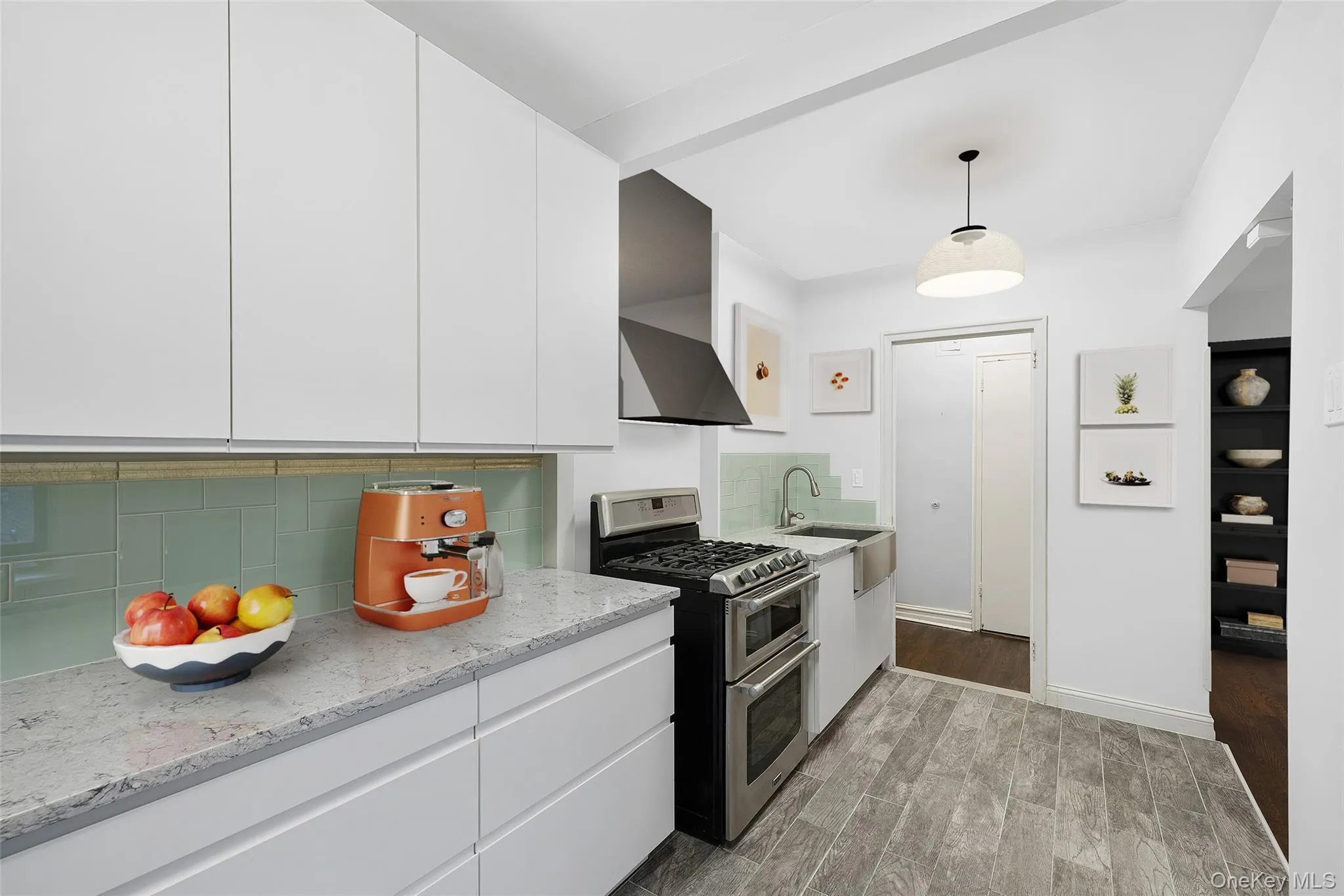 Kitchen with white cabinets, range with two ovens, decorative backsplash, light wood-type flooring, and hanging light fixtures Kitchen with white cabinets, range with two ovens, decorative backsplash, light wood-type flooring, and hanging light fixtures