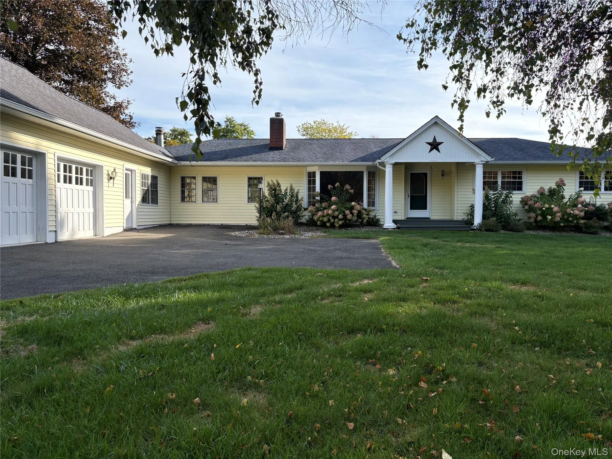Ranch-style house with a front yard, a garage, a chimney, driveway, and covered porch Ranch-style house with a front yard, a garage, a chimney, driveway, and covered porch