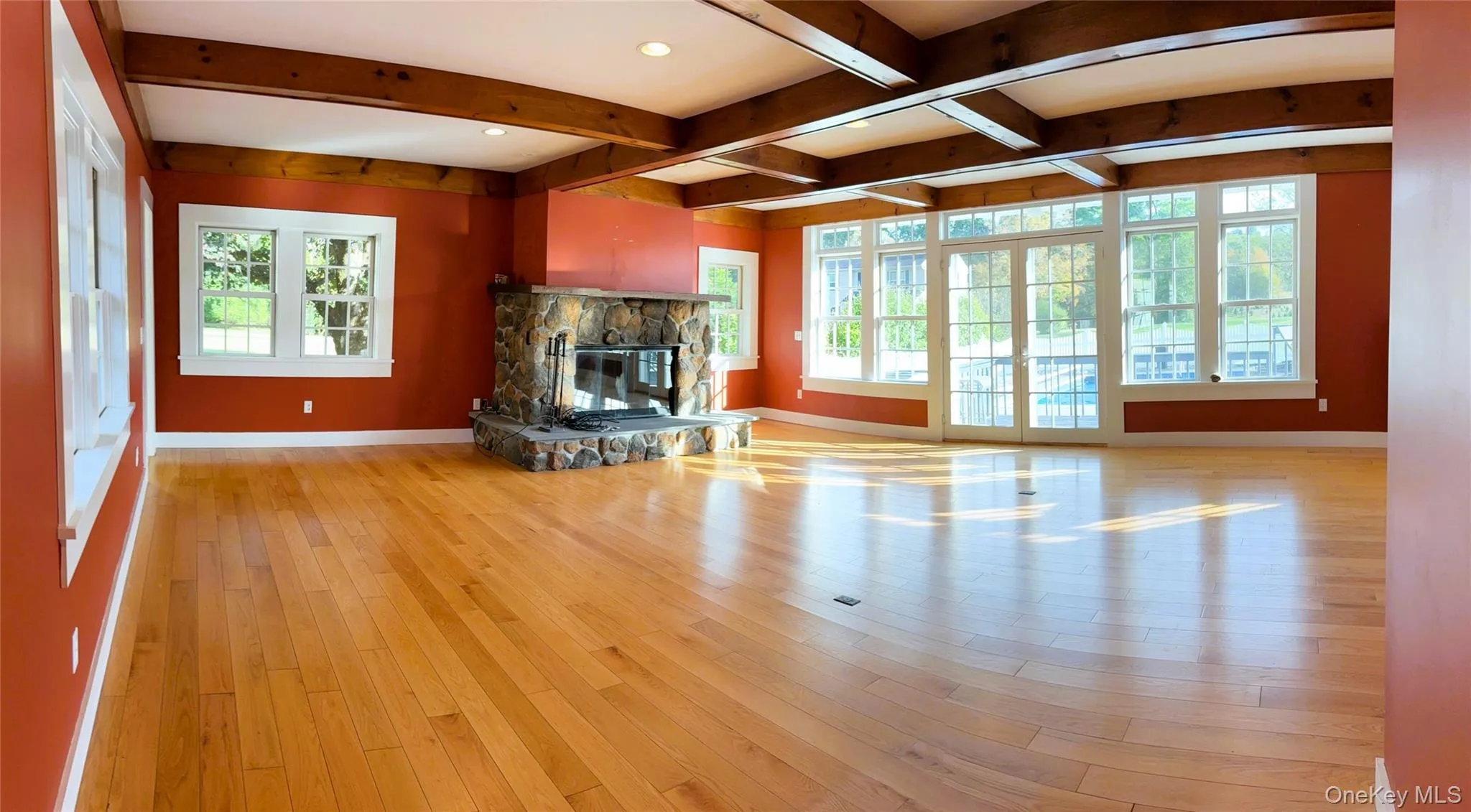 Unfurnished living room featuring beam ceiling, a fireplace, light wood-type flooring, and coffered ceiling Unfurnished living room featuring beam ceiling, a fireplace, light wood-type flooring, and coffered ceiling