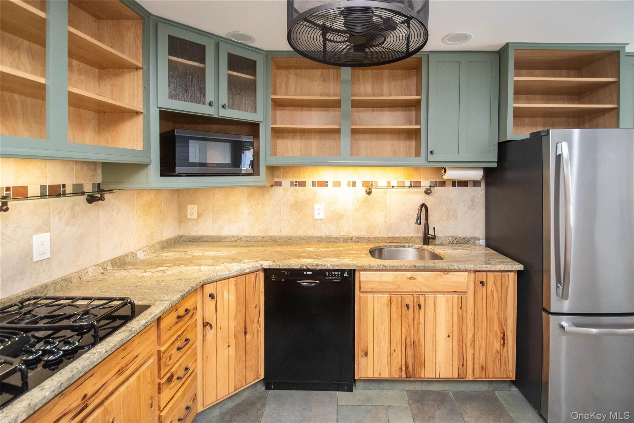 Kitchen featuring open shelves, black appliances, green cabinetry, and backsplash Kitchen featuring open shelves, black appliances, green cabinetry, and backsplash