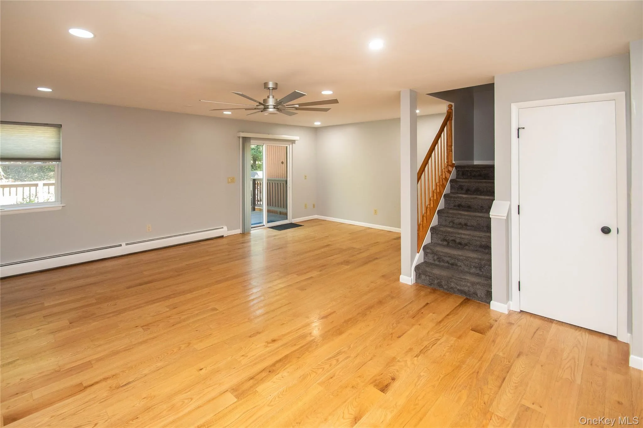 Unfurnished living room with recessed lighting, stairway, light wood finished floors, a baseboard radiator, and ceiling fan Unfurnished living room with recessed lighting, stairway, light wood finished floors, a baseboard radiator, and ceiling fan