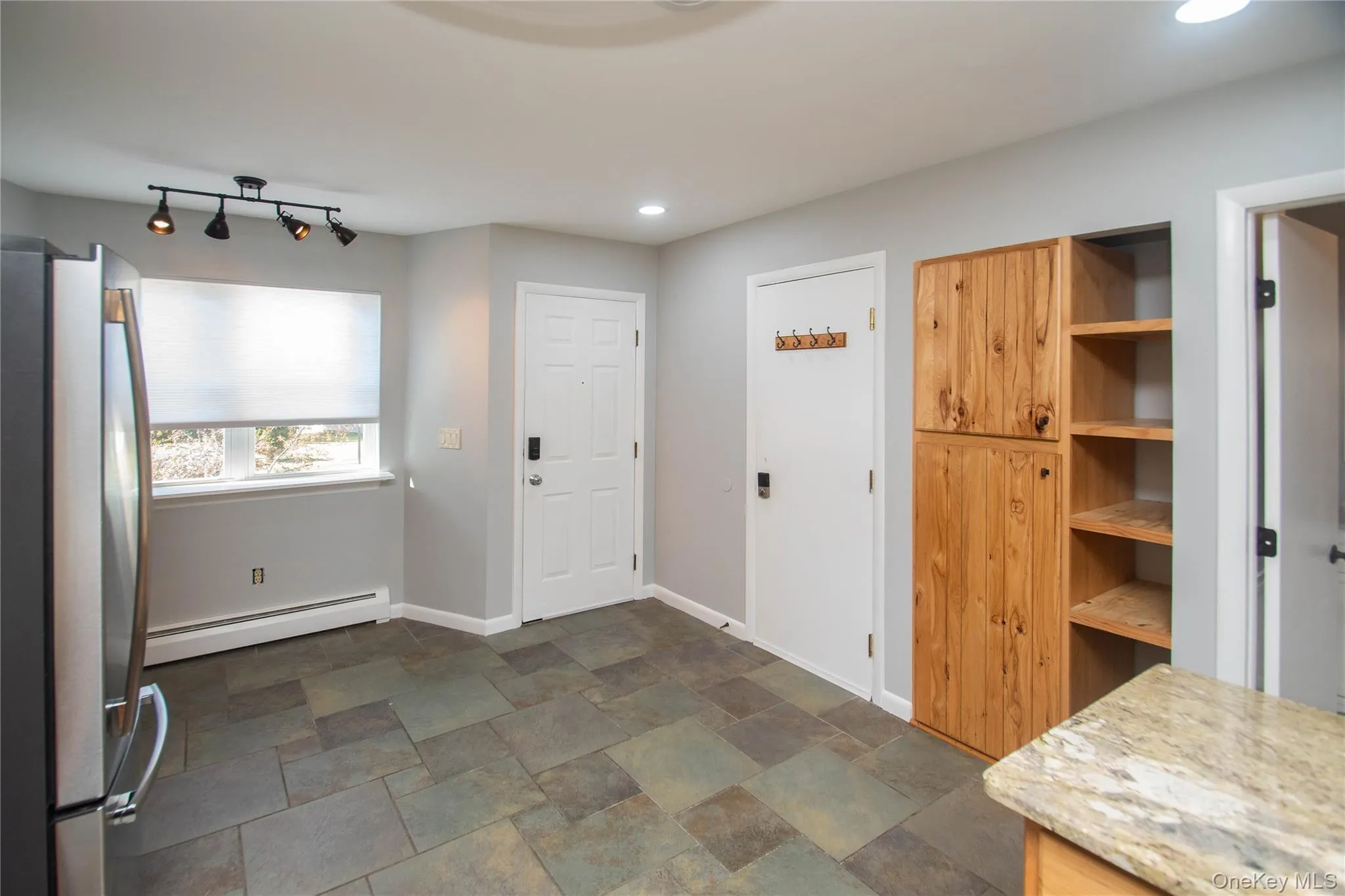 Kitchen with freestanding refrigerator, dark stone finish flooring, a baseboard radiator, recessed lighting, and open shelves Kitchen with freestanding refrigerator, dark stone finish flooring, a baseboard radiator, recessed lighting, and open shelves