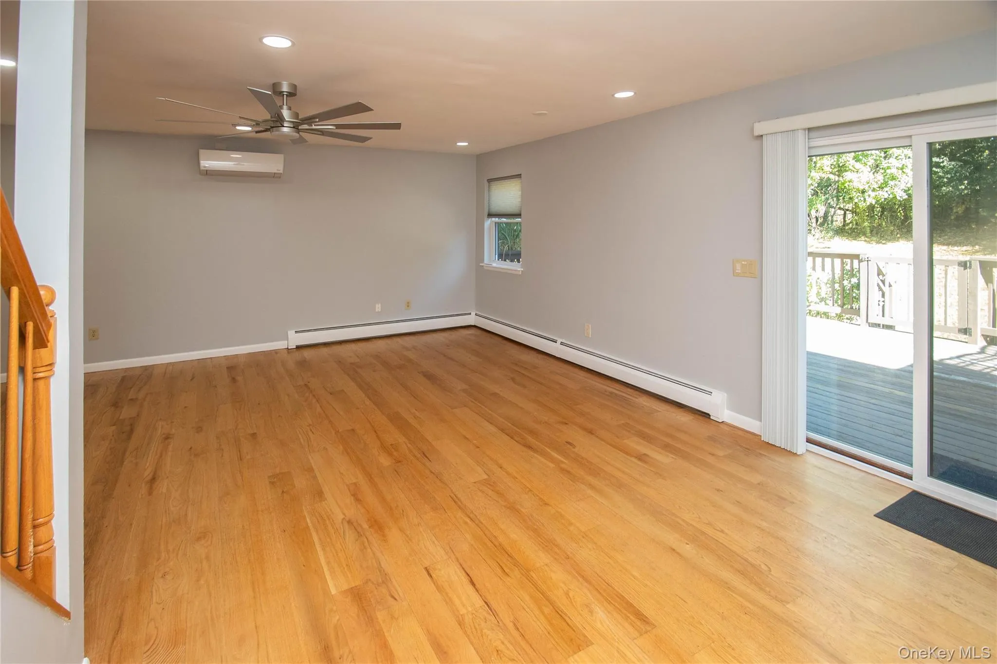Unfurnished room with recessed lighting, a baseboard heating unit, light wood-style floors, a ceiling fan, and a wall mounted air conditioner Unfurnished room with recessed lighting, a baseboard heating unit, light wood-style floors, a ceiling fan, and a wall mounted air conditioner