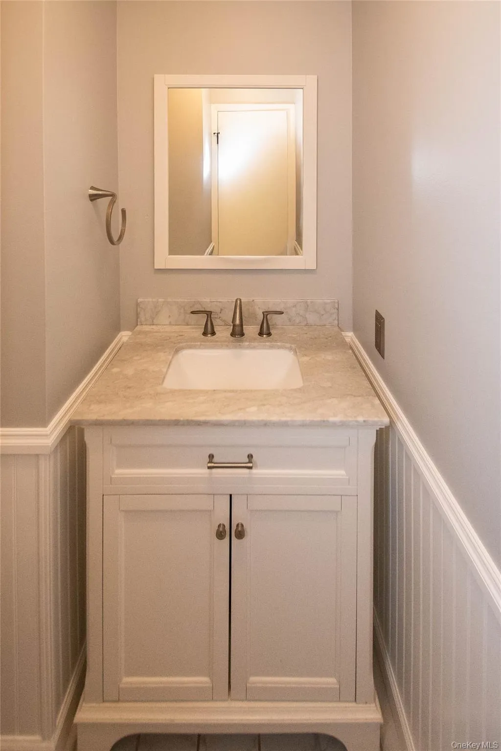 Bathroom featuring wainscoting, vanity, and a decorative wall Bathroom featuring wainscoting, vanity, and a decorative wall