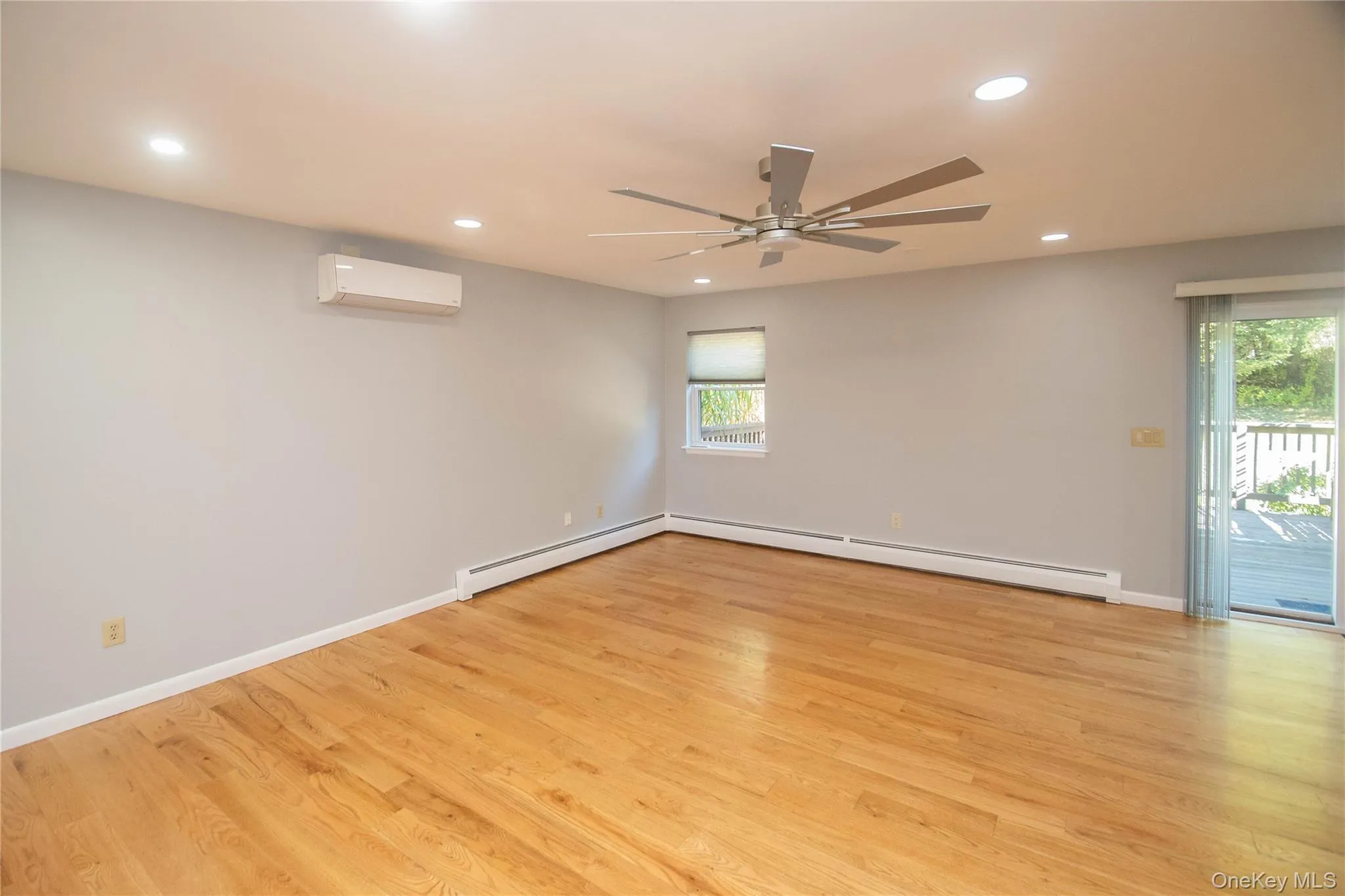 Empty room with light wood finished floors, recessed lighting, a baseboard radiator, a ceiling fan, and a wall mounted AC Empty room with light wood finished floors, recessed lighting, a baseboard radiator, a ceiling fan, and a wall mounted AC