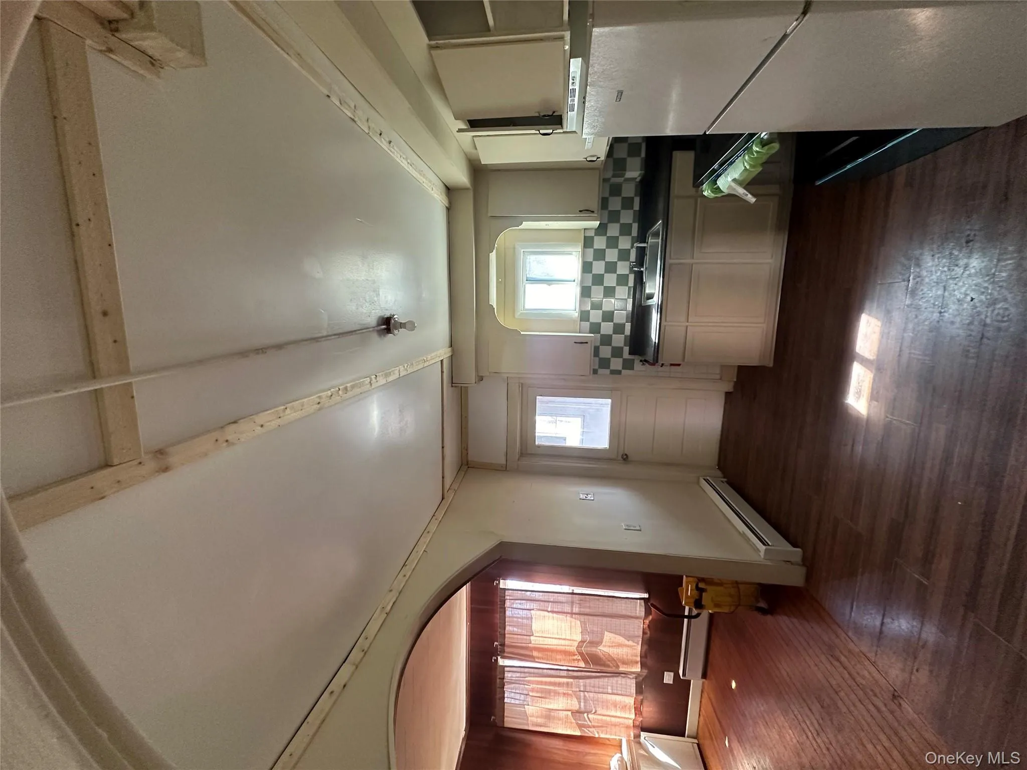 Kitchen featuring refrigerator, tasteful backsplash, dark wood-style floors, baseboard heating, and dark countertops Kitchen featuring refrigerator, tasteful backsplash, dark wood-style floors, baseboard heating, and dark countertops