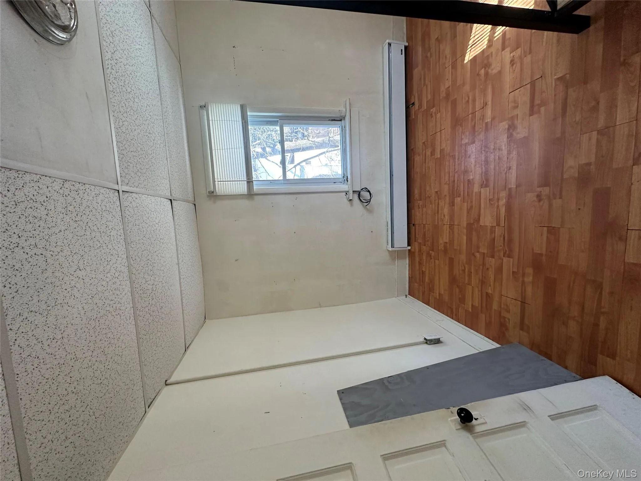 Empty room featuring a paneled ceiling, wood finished floors, and baseboard heating Empty room featuring a paneled ceiling, wood finished floors, and baseboard heating