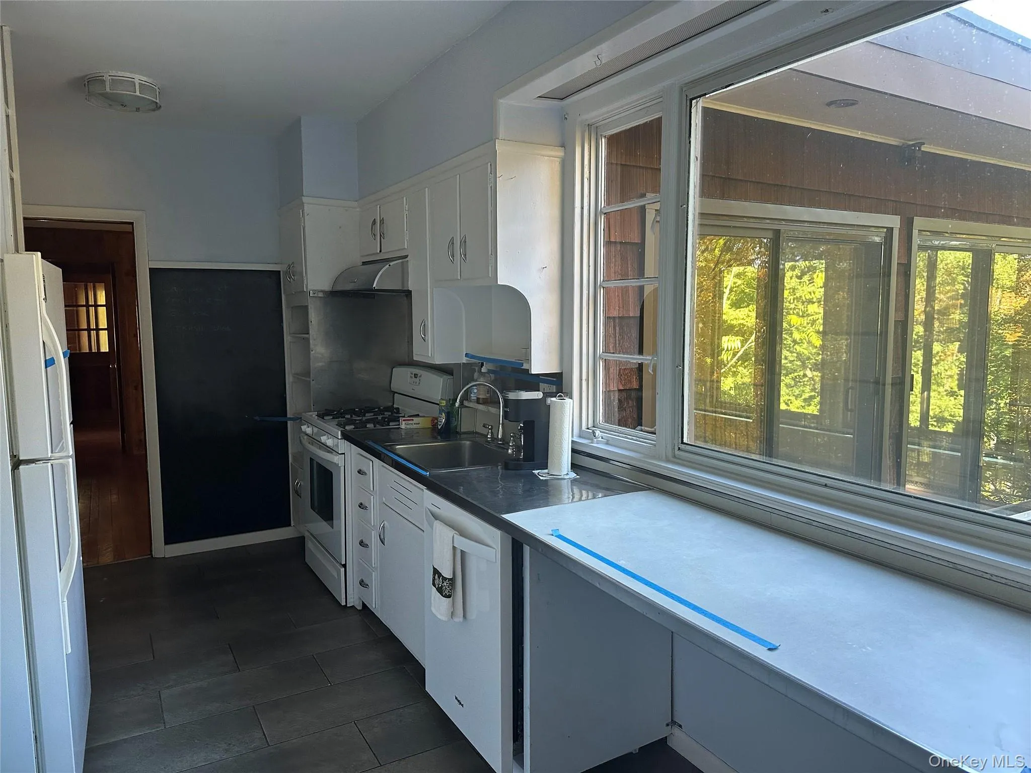 Kitchen with white cabinetry, white appliances, and range hood Kitchen with white cabinetry, white appliances, and range hood