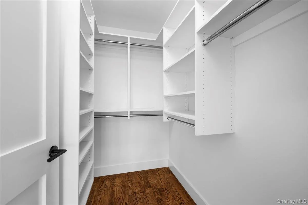 Walk-in closet featuring dark wood-style flooring Walk-in closet featuring dark wood-style flooring