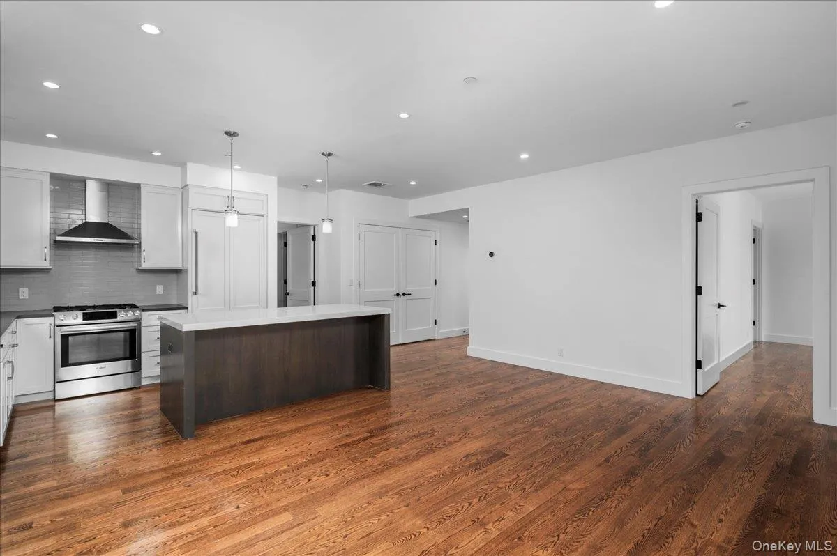 Kitchen featuring stainless steel gas range oven, tasteful backsplash, wall chimney exhaust hood, dark brown cabinets, and dark wood finished floors Kitchen featuring stainless steel gas range oven, tasteful backsplash, wall chimney exhaust hood, dark brown cabinets, and dark wood finished floors