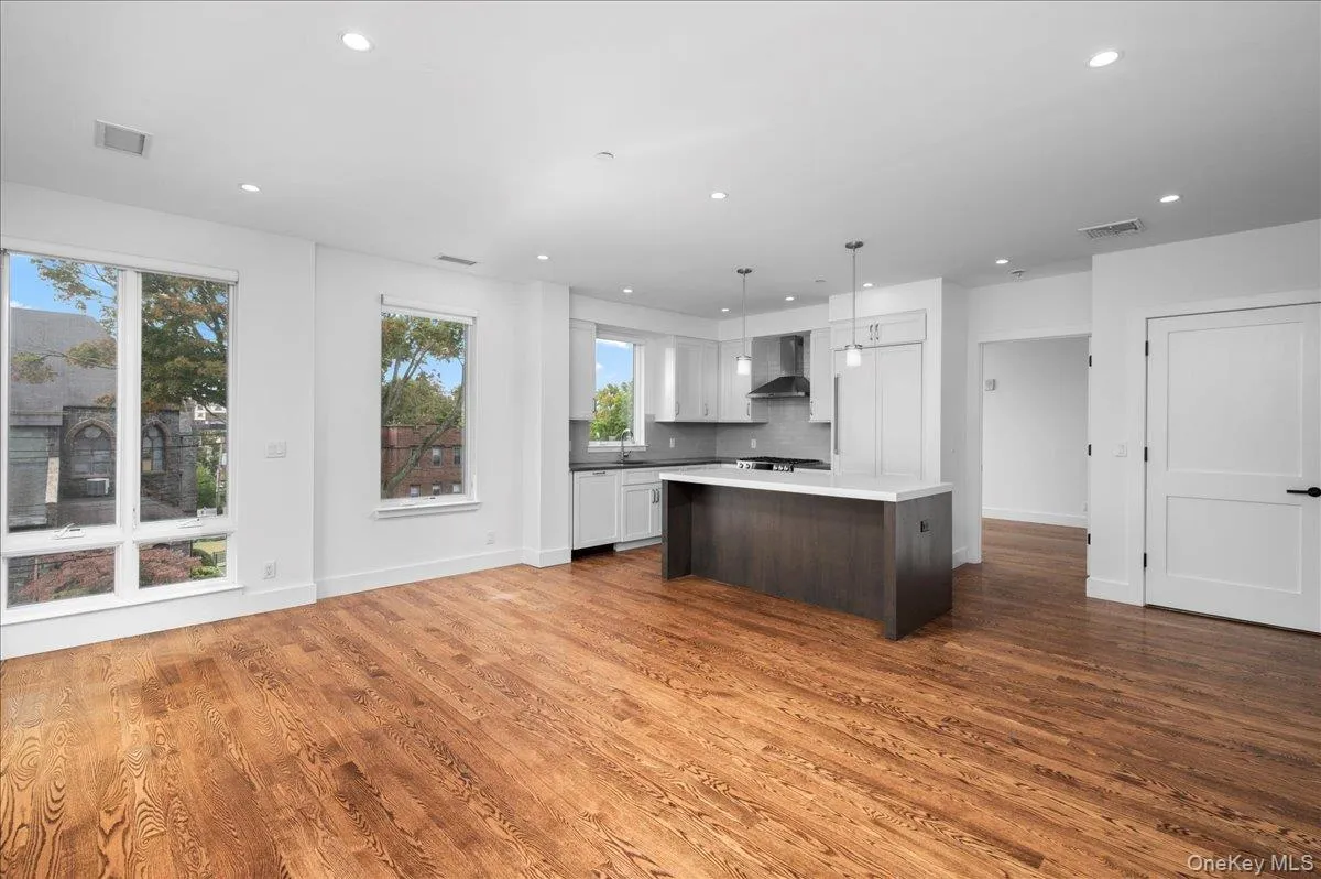 Kitchen featuring dark brown cabinets, white cabinets, light countertops, hanging light fixtures, and open floor plan Kitchen featuring dark brown cabinets, white cabinets, light countertops, hanging light fixtures, and open floor plan