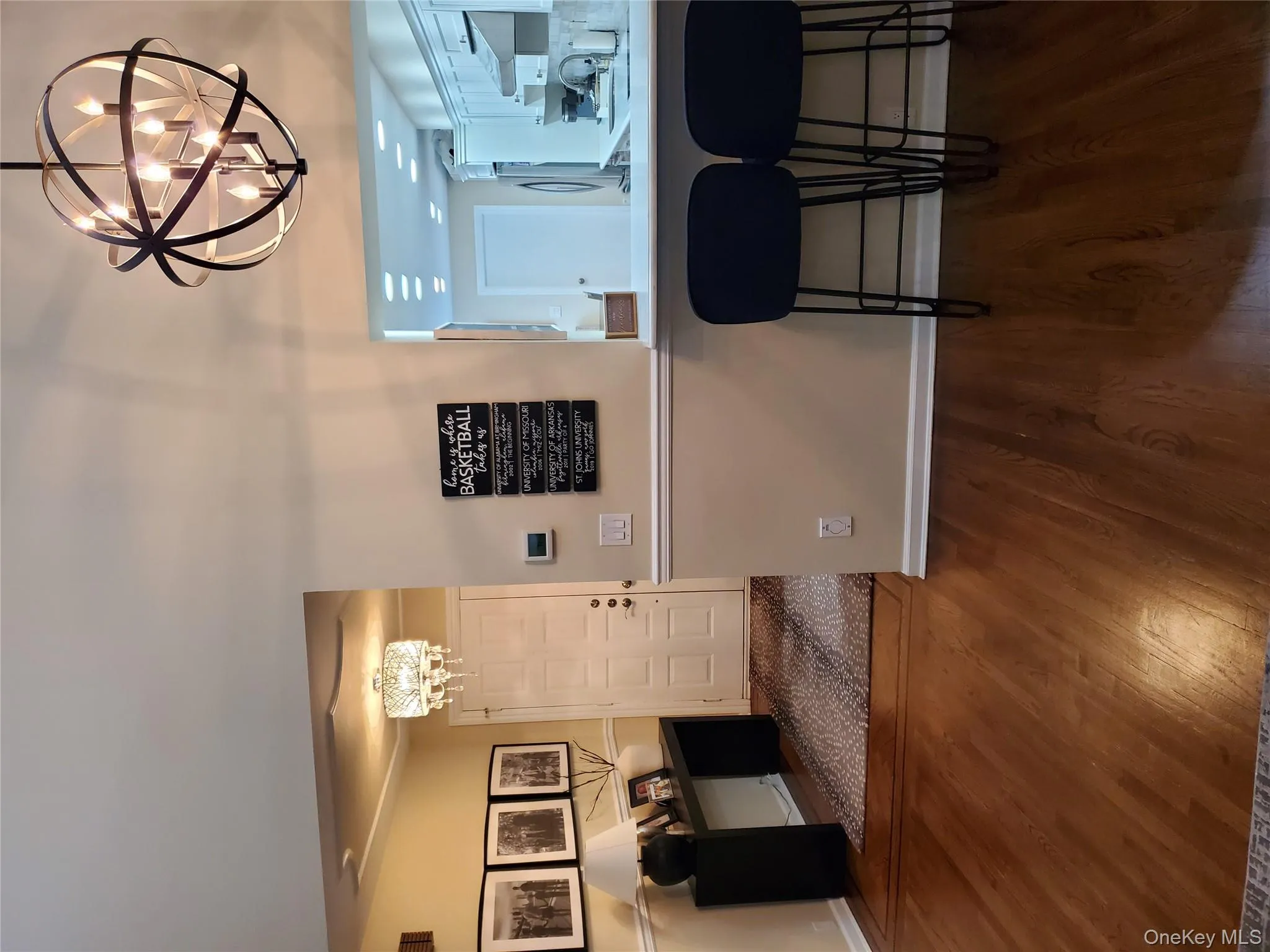 Kitchen with a chandelier, dark wood-style floors, a kitchen breakfast bar, light countertops, and ventilation hood Kitchen with a chandelier, dark wood-style floors, a kitchen breakfast bar, light countertops, and ventilation hood