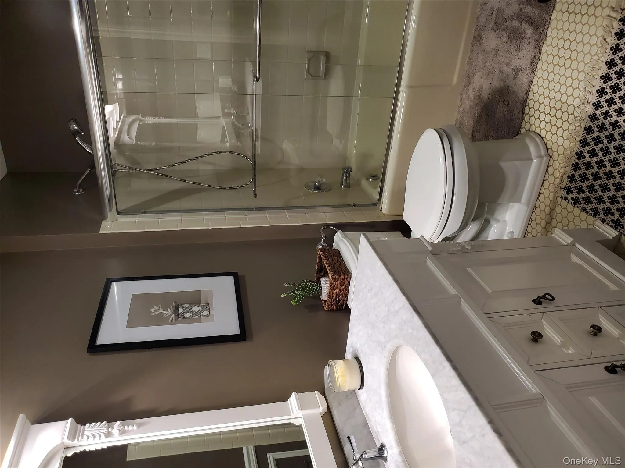 Bathroom featuring shower / bath combination with glass door, vanity, and light tile patterned flooring Bathroom featuring shower / bath combination with glass door, vanity, and light tile patterned flooring