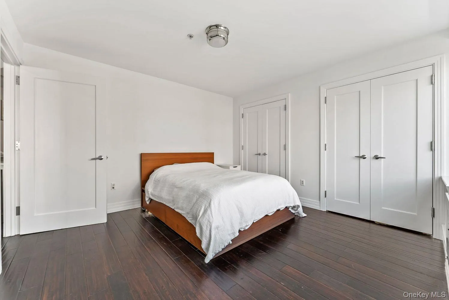 Bedroom with two closets and dark wood finished floors Bedroom with two closets and dark wood finished floors