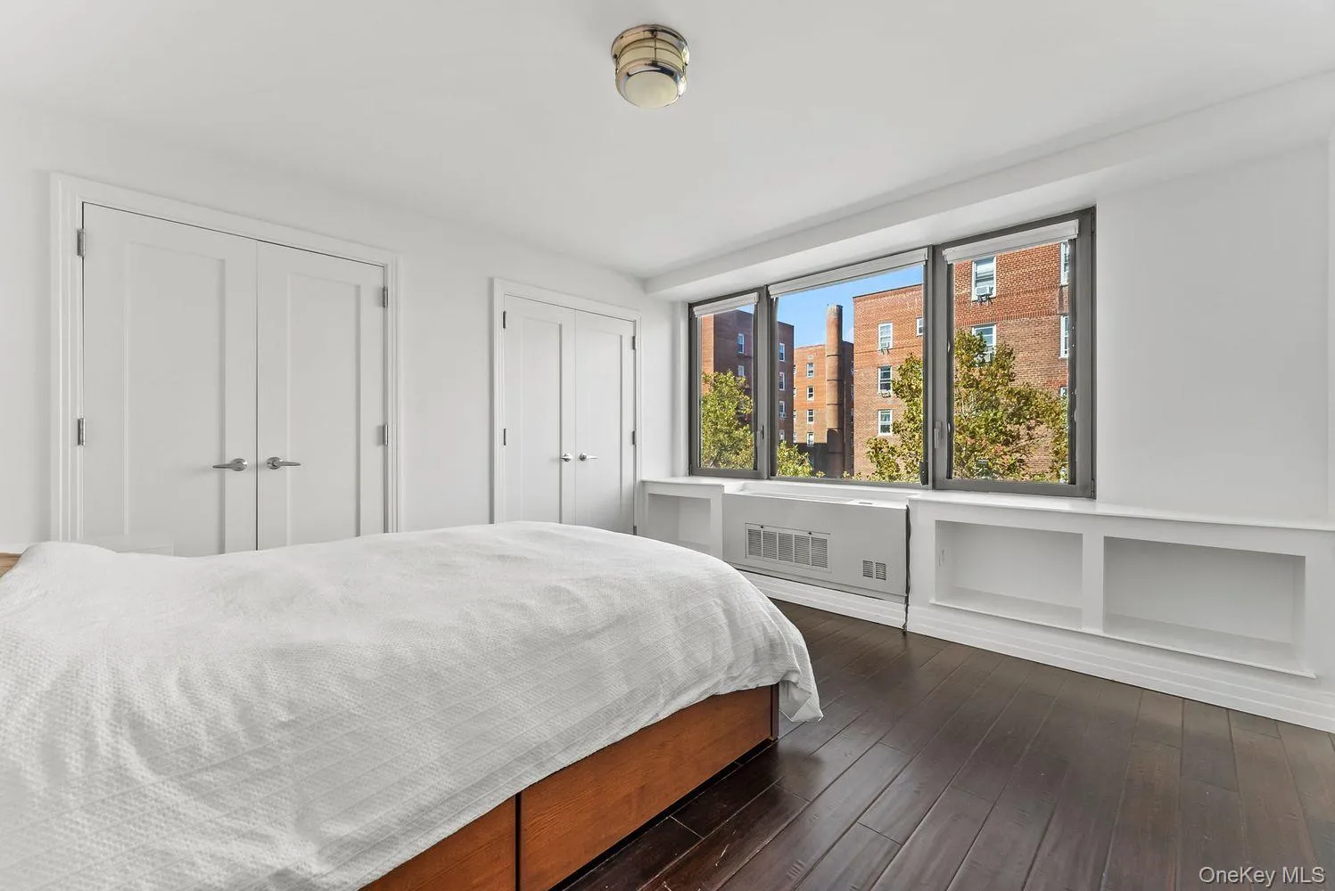Bedroom featuring multiple closets and dark wood-style floors Bedroom featuring multiple closets and dark wood-style floors