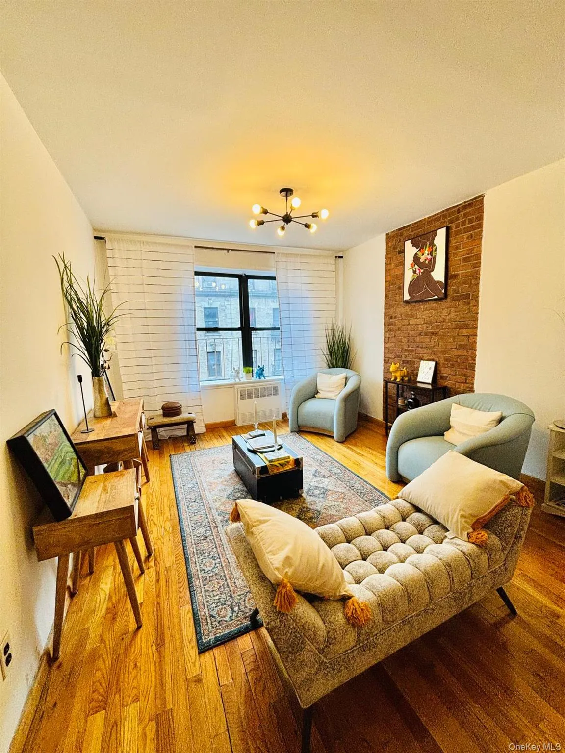 Living room featuring wood finished floors, a chandelier, and radiator Living room featuring wood finished floors, a chandelier, and radiator