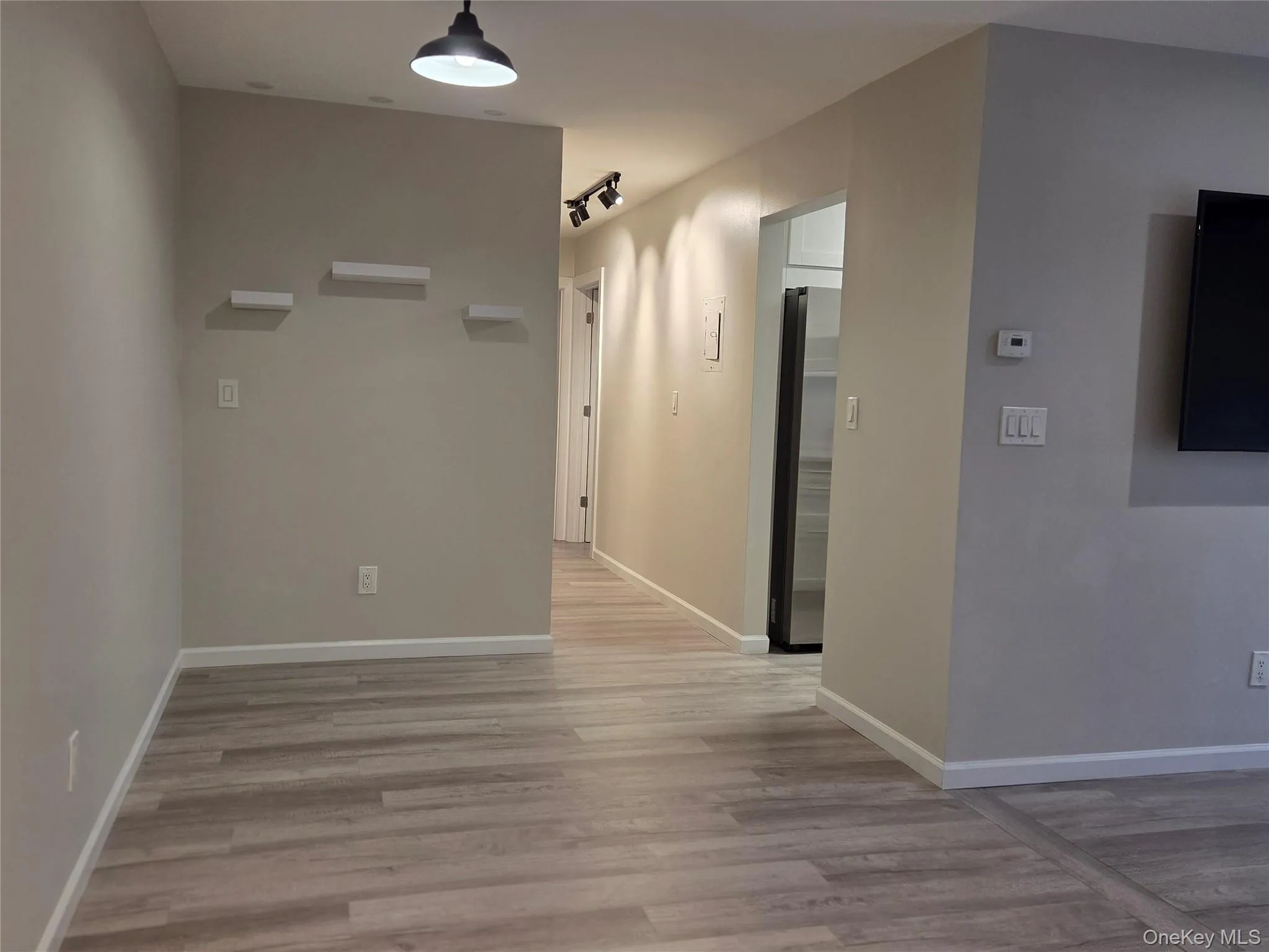 Corridor featuring light wood-style floors and baseboards Corridor featuring light wood-style floors and baseboards