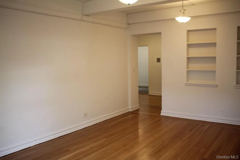 Unfurnished room featuring dark wood-style floors and built in shelves Unfurnished room featuring dark wood-style floors and built in shelves