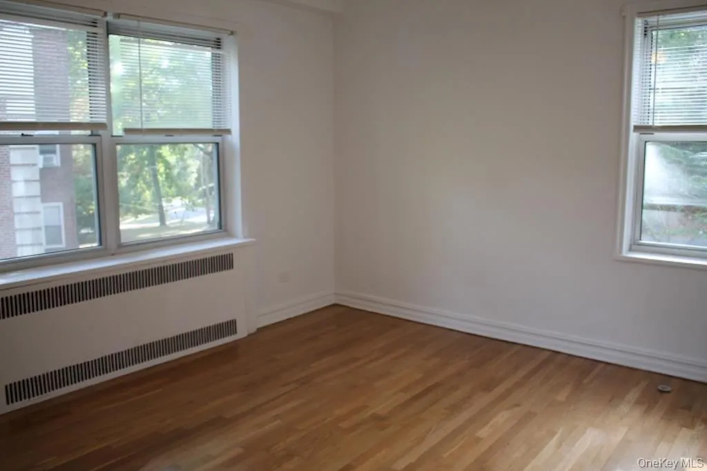 Spare room featuring radiator heating unit and wood finished floors Spare room featuring radiator heating unit and wood finished floors