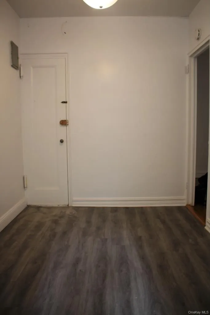 Empty room with dark wood-style flooring and baseboards Empty room with dark wood-style flooring and baseboards