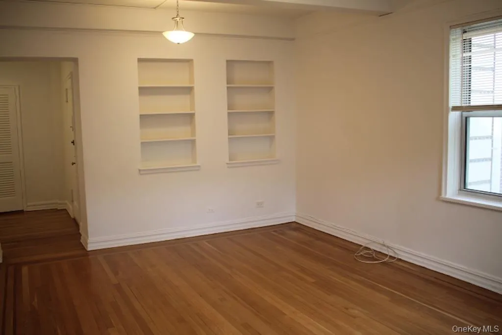 Empty room featuring built in shelves and dark wood finished floors Empty room featuring built in shelves and dark wood finished floors