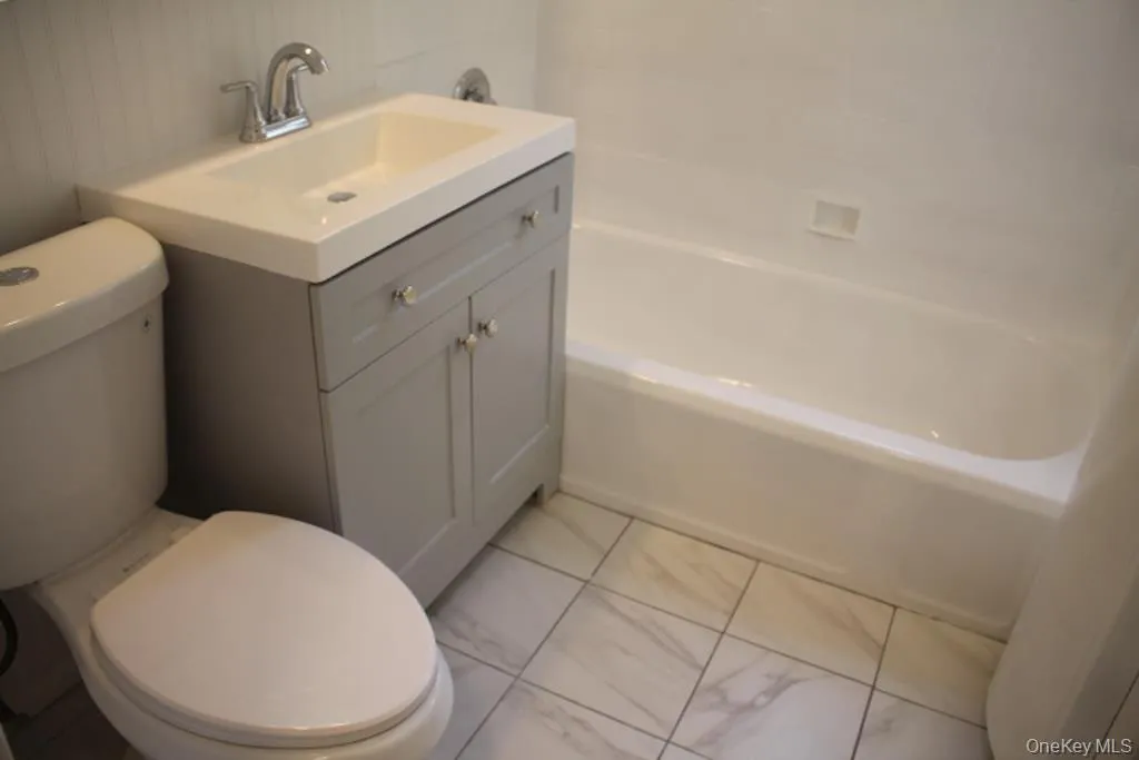 Full bath featuring vanity, bathing tub / shower combination, and light marble finish floors Full bath featuring vanity, bathing tub / shower combination, and light marble finish floors