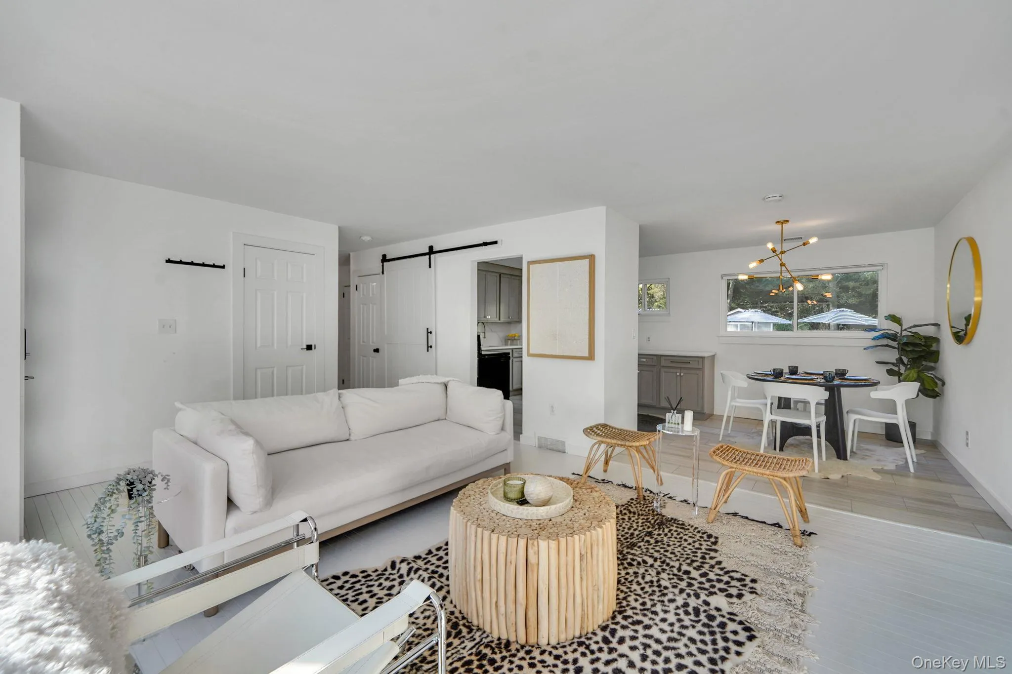 Living area featuring wood finished floors, a barn door, and a chandelier Living area featuring wood finished floors, a barn door, and a chandelier