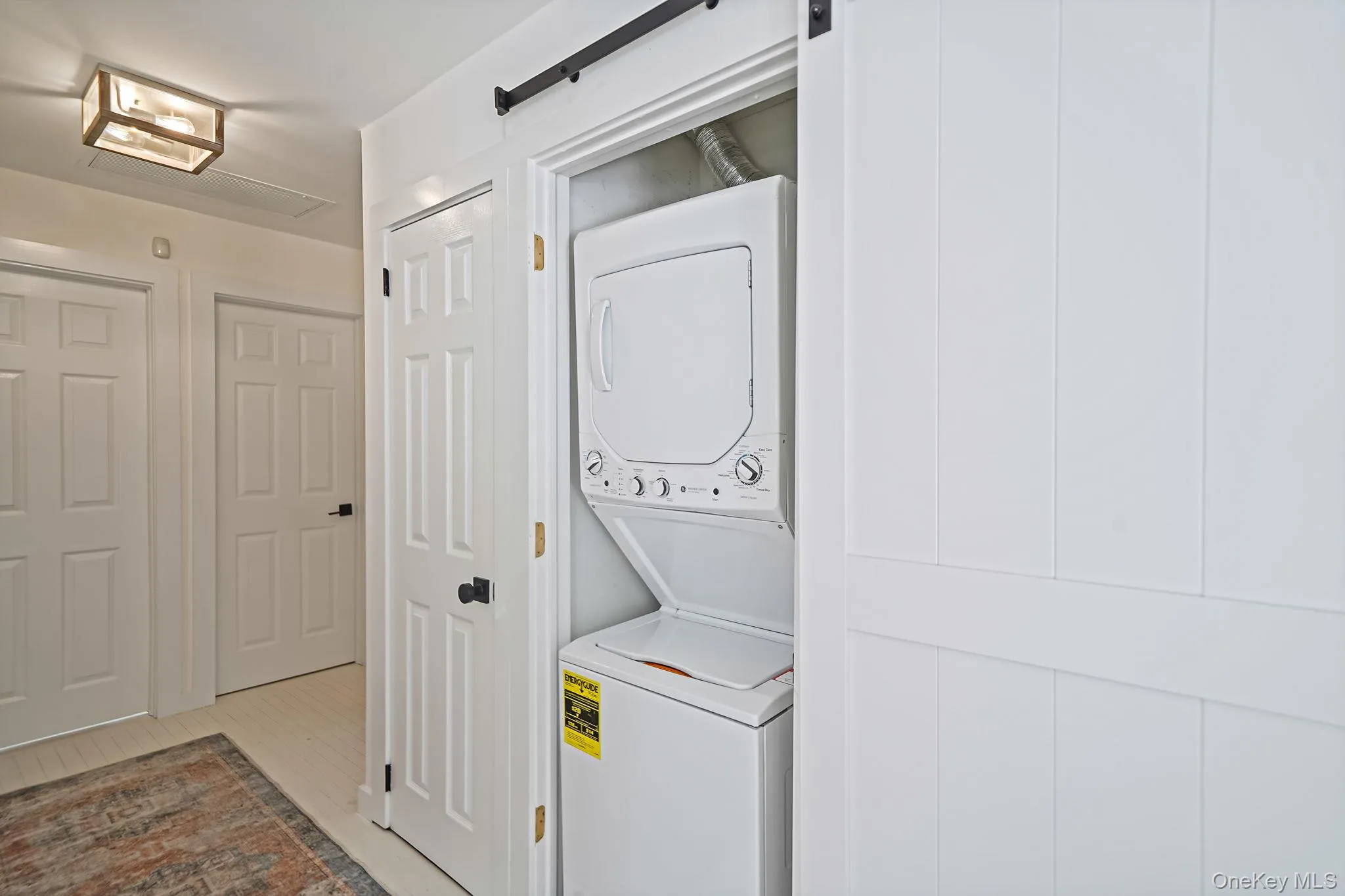 Laundry room with stacked washer and clothes dryer and light wood-style floors Laundry room with stacked washer and clothes dryer and light wood-style floors