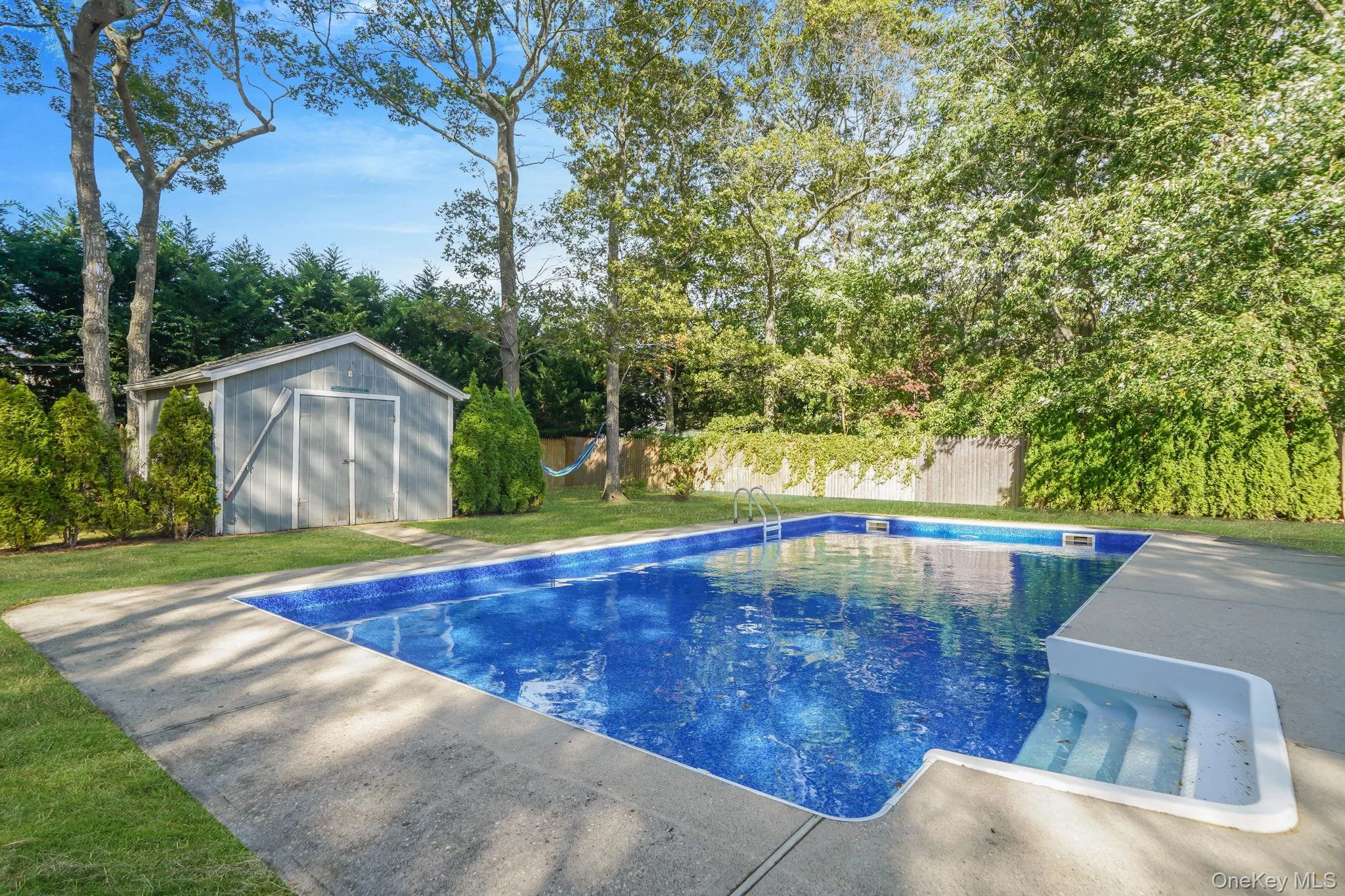 View of swimming pool featuring a fenced backyard, a shed, and view of wooded area View of swimming pool featuring a fenced backyard, a shed, and view of wooded area