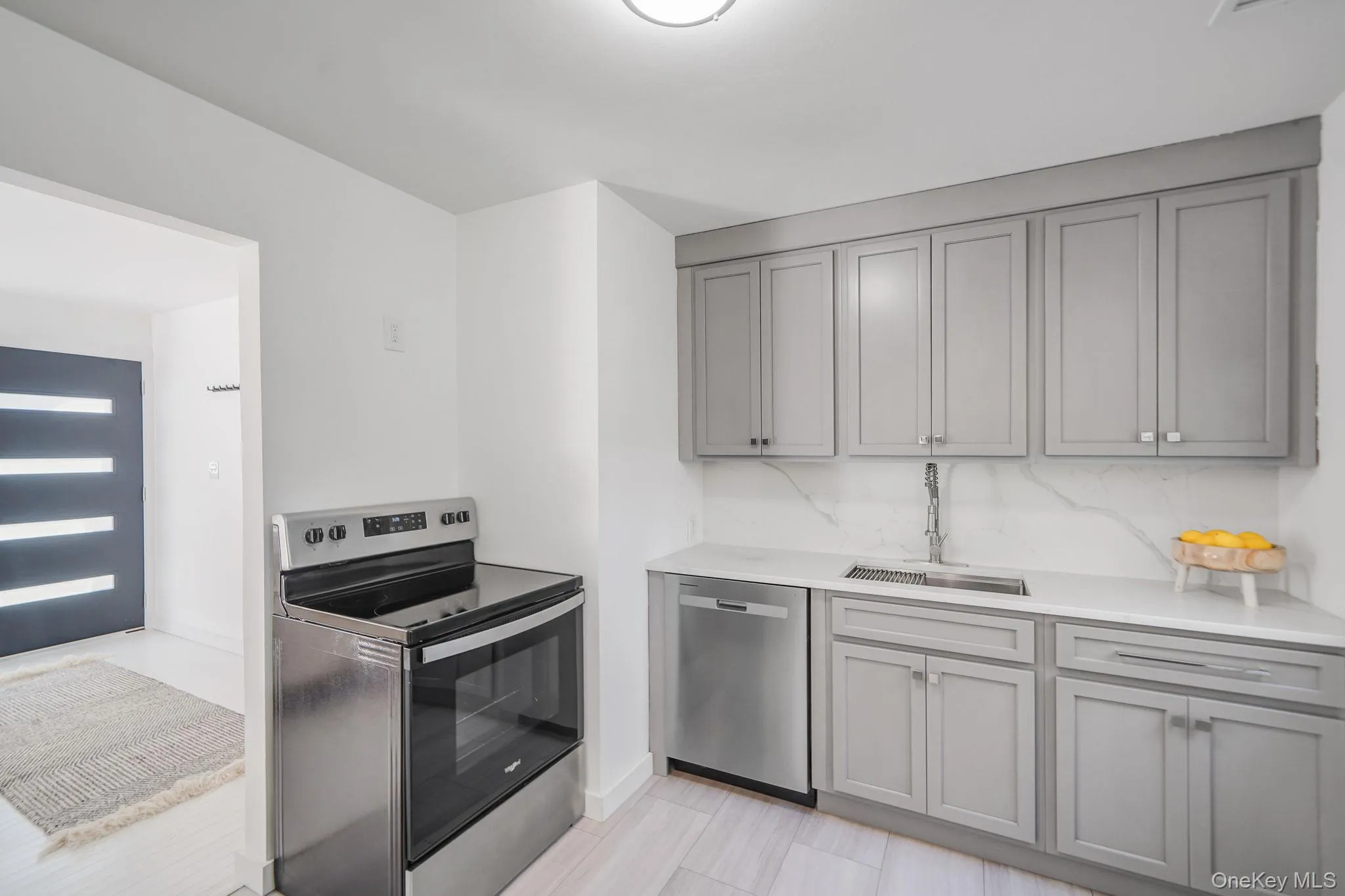 Kitchen featuring appliances with stainless steel finishes, gray cabinets, and light stone counters Kitchen featuring appliances with stainless steel finishes, gray cabinets, and light stone counters