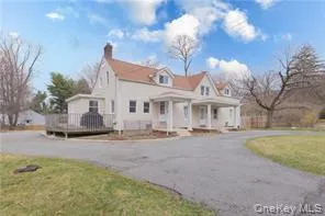 View of property exterior with a lawn, covered porch, a chimney, and curved driveway View of property exterior with a lawn, covered porch, a chimney, and curved driveway