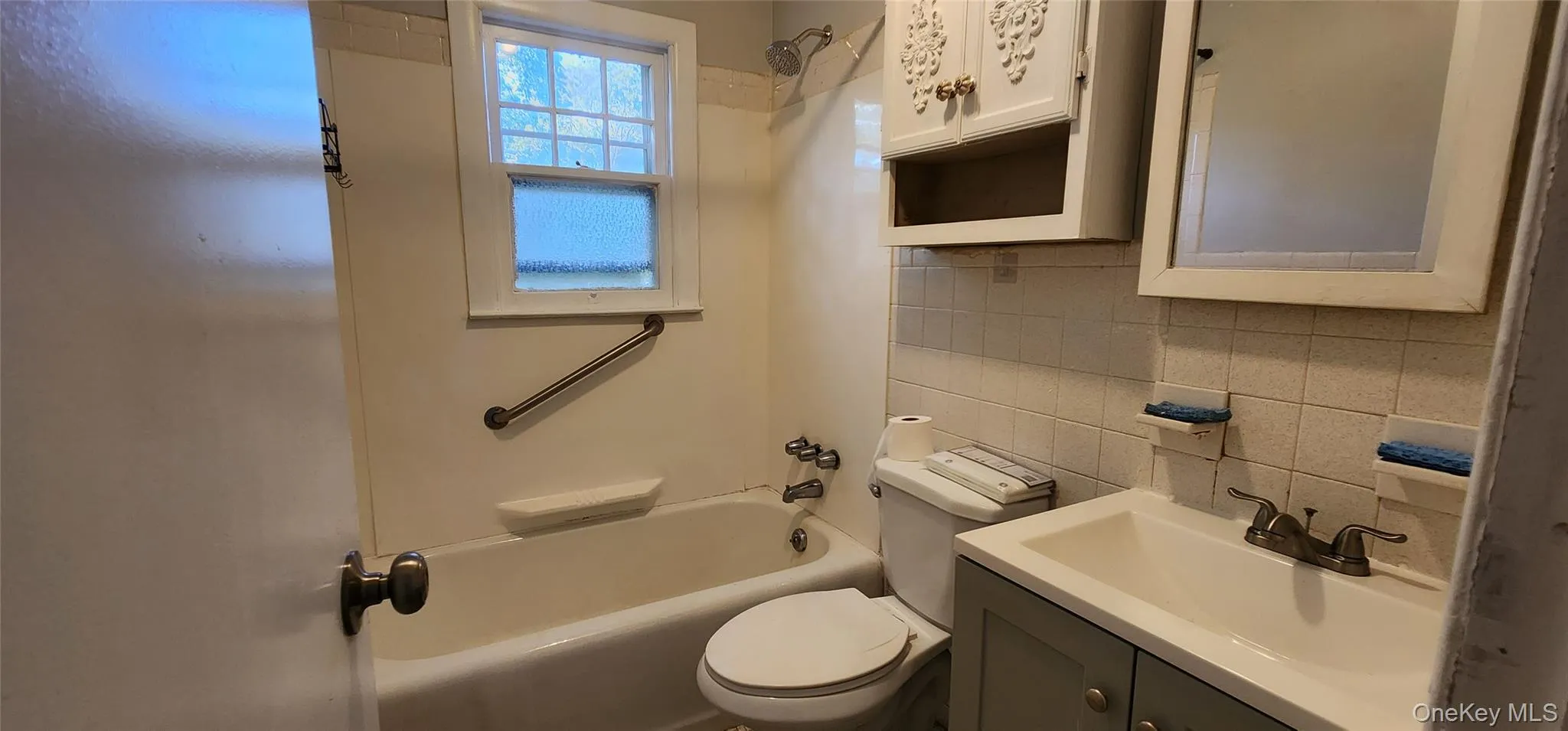 Full bathroom featuring backsplash, vanity, and tub / shower combination Full bathroom featuring backsplash, vanity, and tub / shower combination