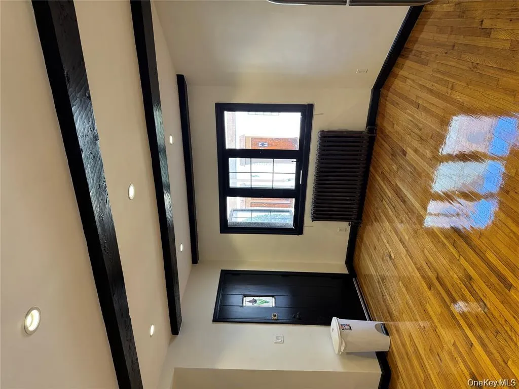 Entrance foyer with beam ceiling, light wood finished floors, radiator, and recessed lighting Entrance foyer with beam ceiling, light wood finished floors, radiator, and recessed lighting