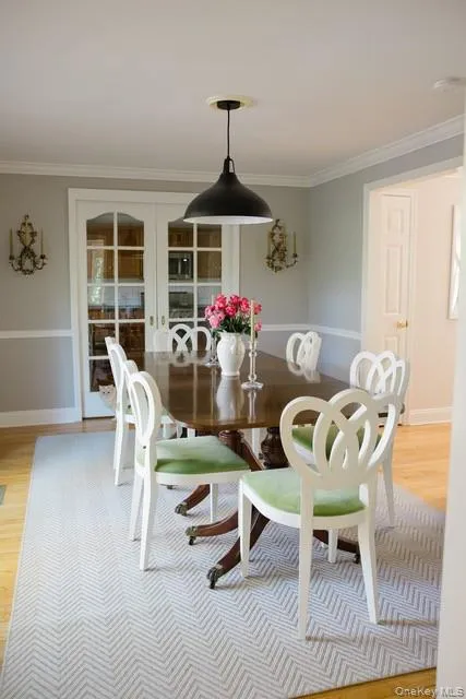 Dining space featuring light wood-style flooring, ornamental molding, and french doors Dining space featuring light wood-style flooring, ornamental molding, and french doors