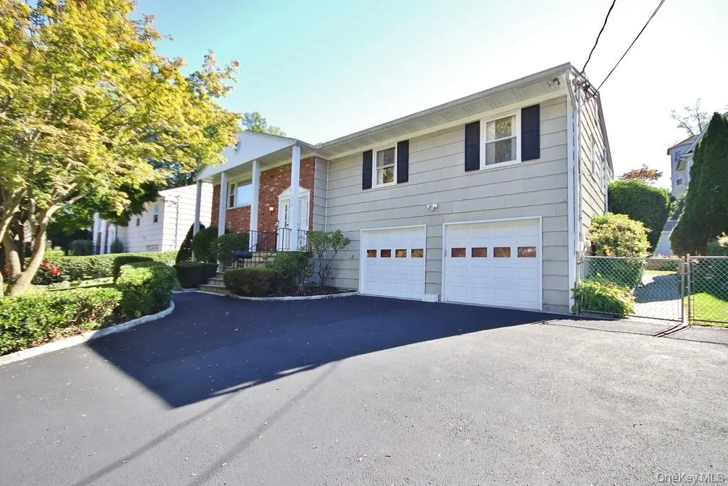 Bi-level home with a garage, driveway, and a gate Bi-level home with a garage, driveway, and a gate