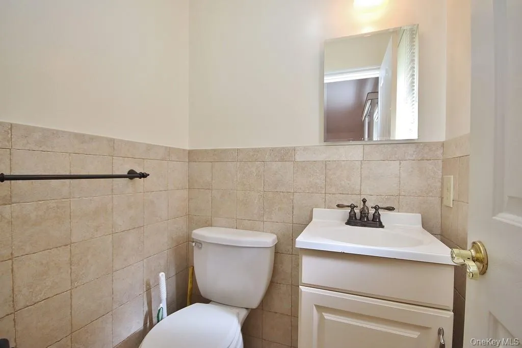 Half bathroom with vanity, tile walls, and wainscoting Half bathroom with vanity, tile walls, and wainscoting