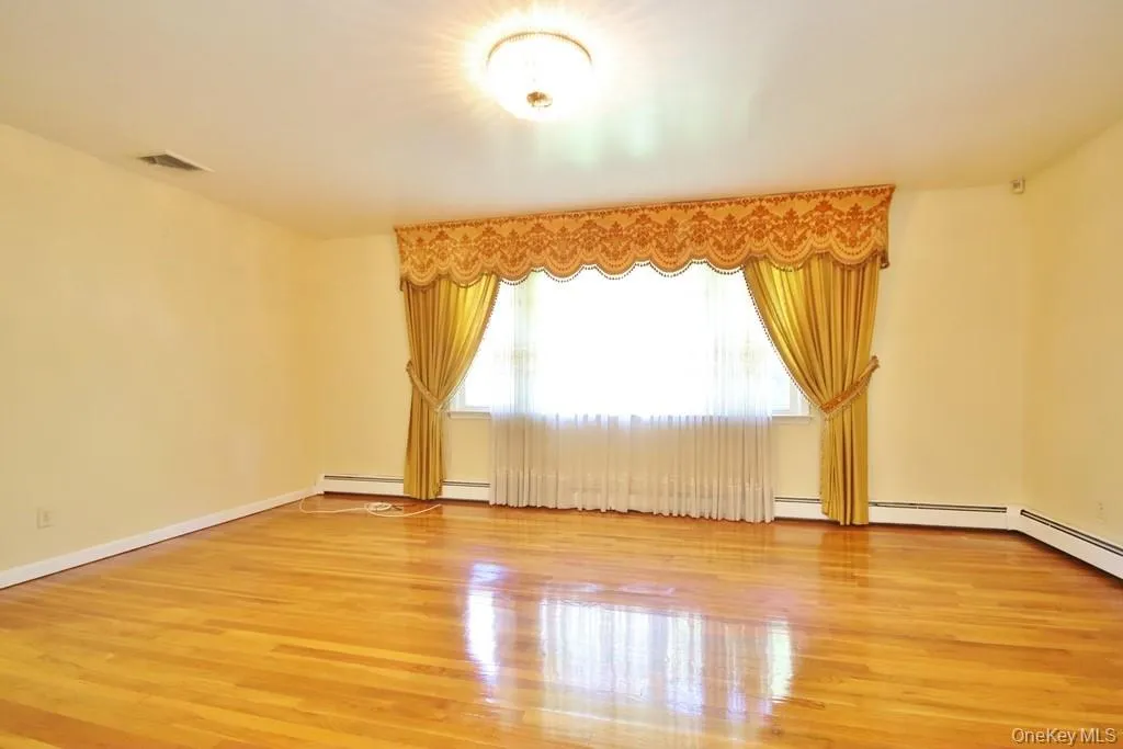 Spare room featuring light wood-style flooring and baseboard heating Spare room featuring light wood-style flooring and baseboard heating