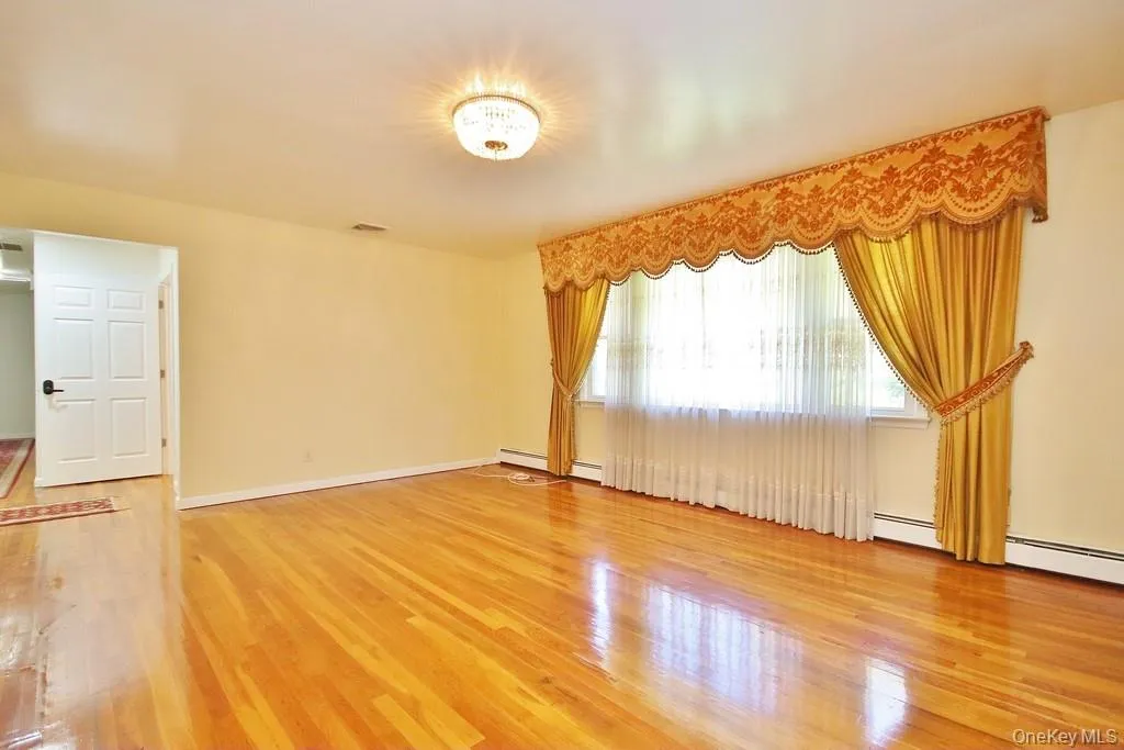 Spare room featuring light wood-style floors and a baseboard heating unit Spare room featuring light wood-style floors and a baseboard heating unit