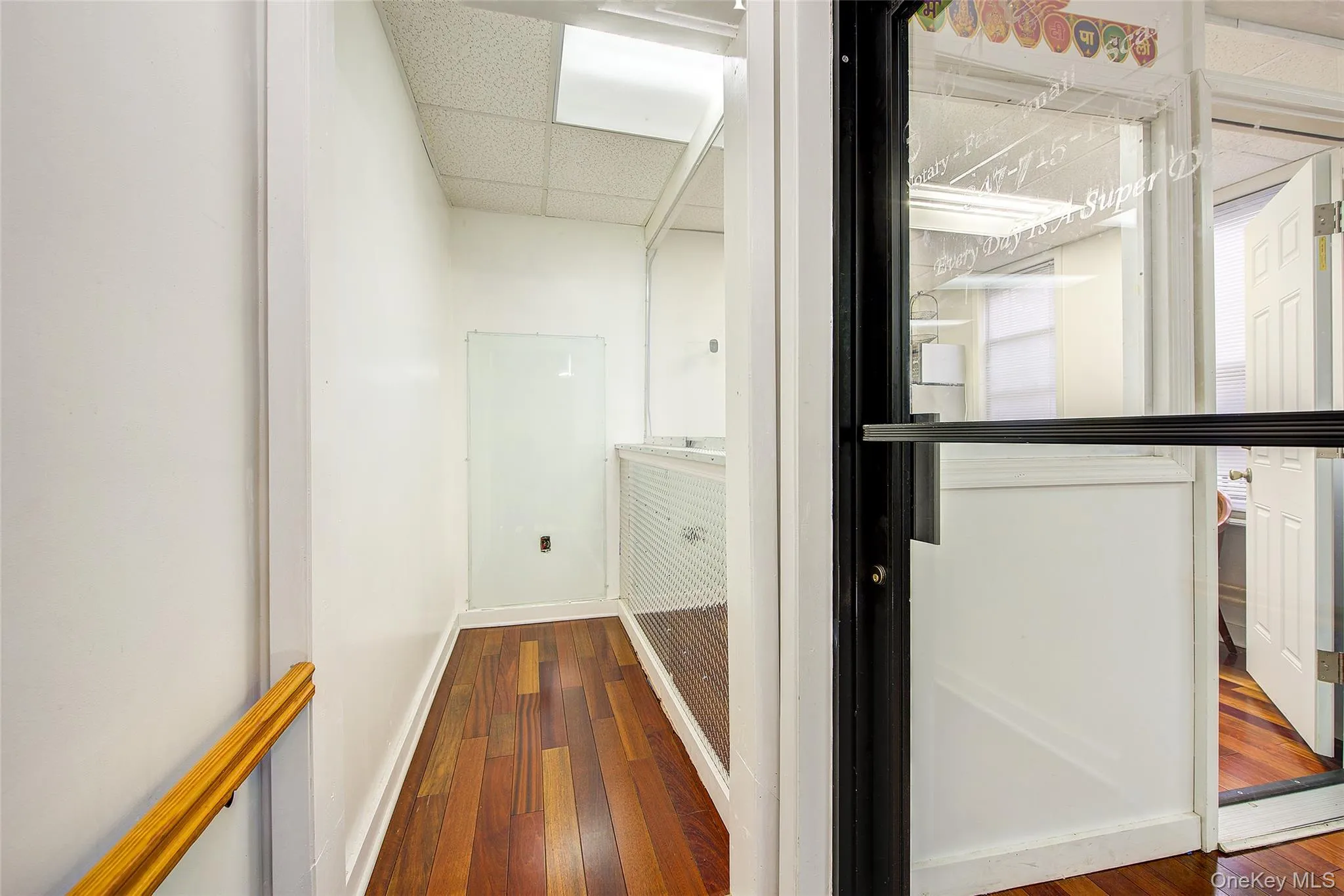 Hall featuring a paneled ceiling, wood-type flooring, and baseboards Hall featuring a paneled ceiling, wood-type flooring, and baseboards