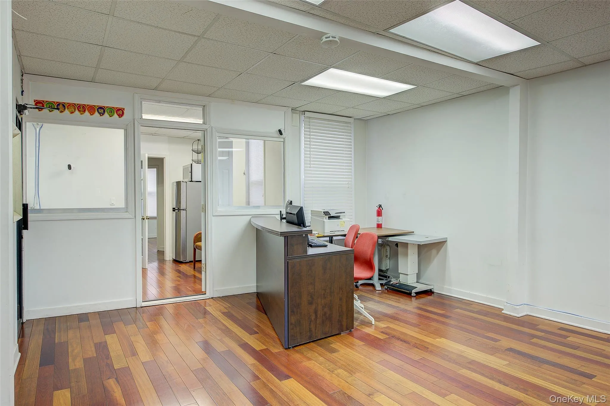 Office area with a paneled ceiling, baseboards, and hardwood / wood-style flooring Office area with a paneled ceiling, baseboards, and hardwood / wood-style flooring