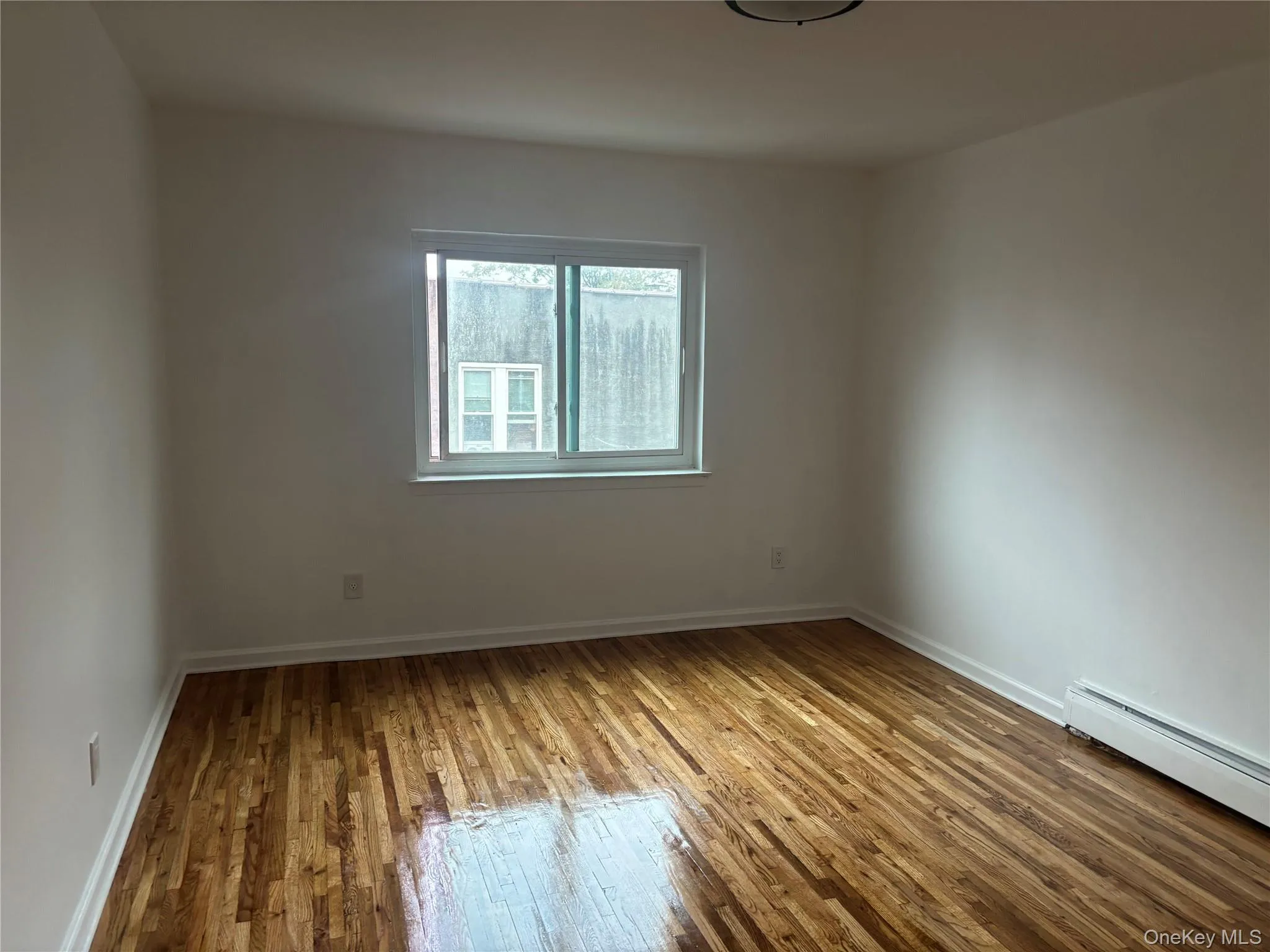 Unfurnished room featuring hardwood / wood-style floors and baseboard heating Unfurnished room featuring hardwood / wood-style floors and baseboard heating
