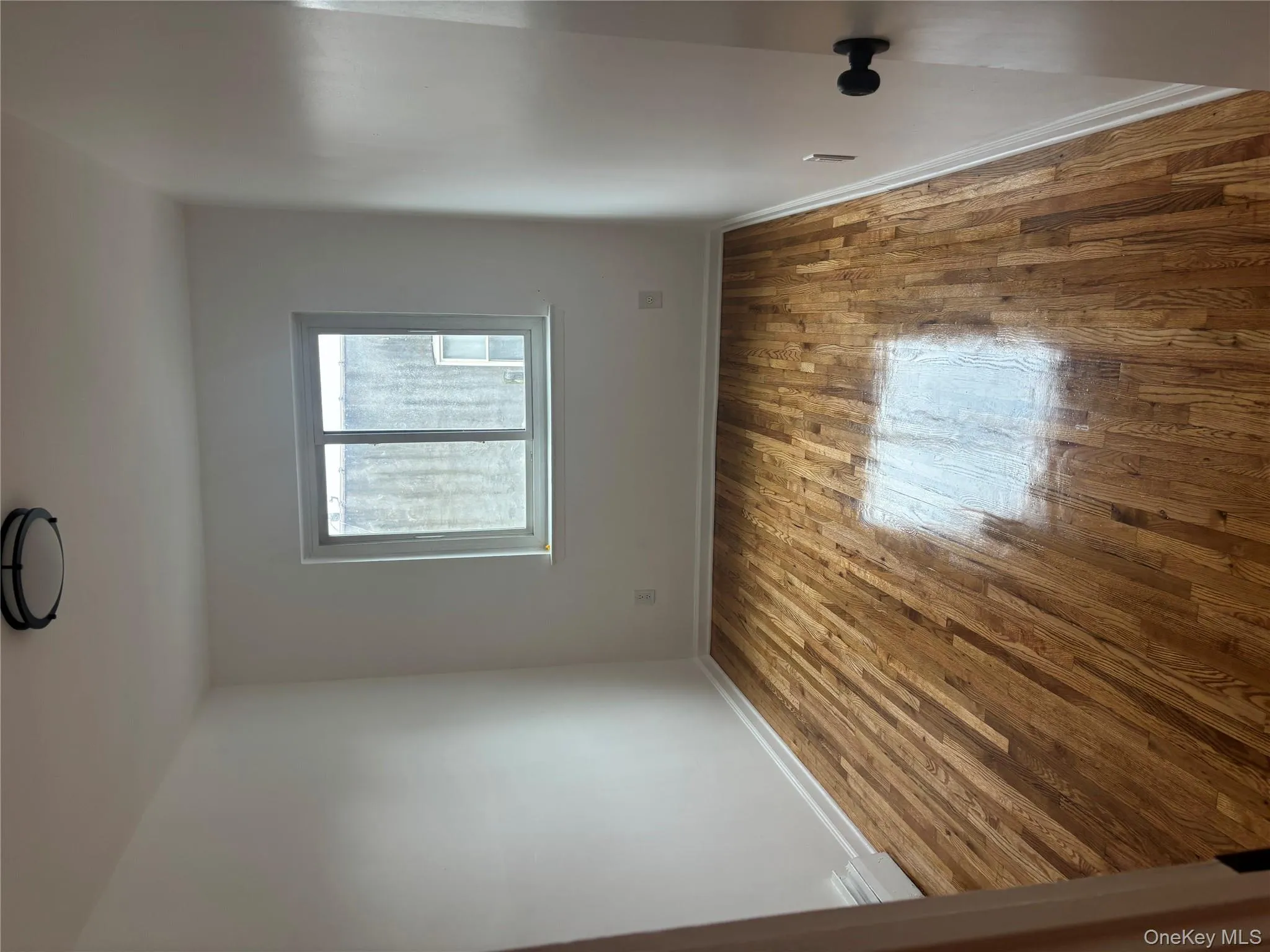 Empty room with wood-type flooring and a baseboard radiator Empty room with wood-type flooring and a baseboard radiator