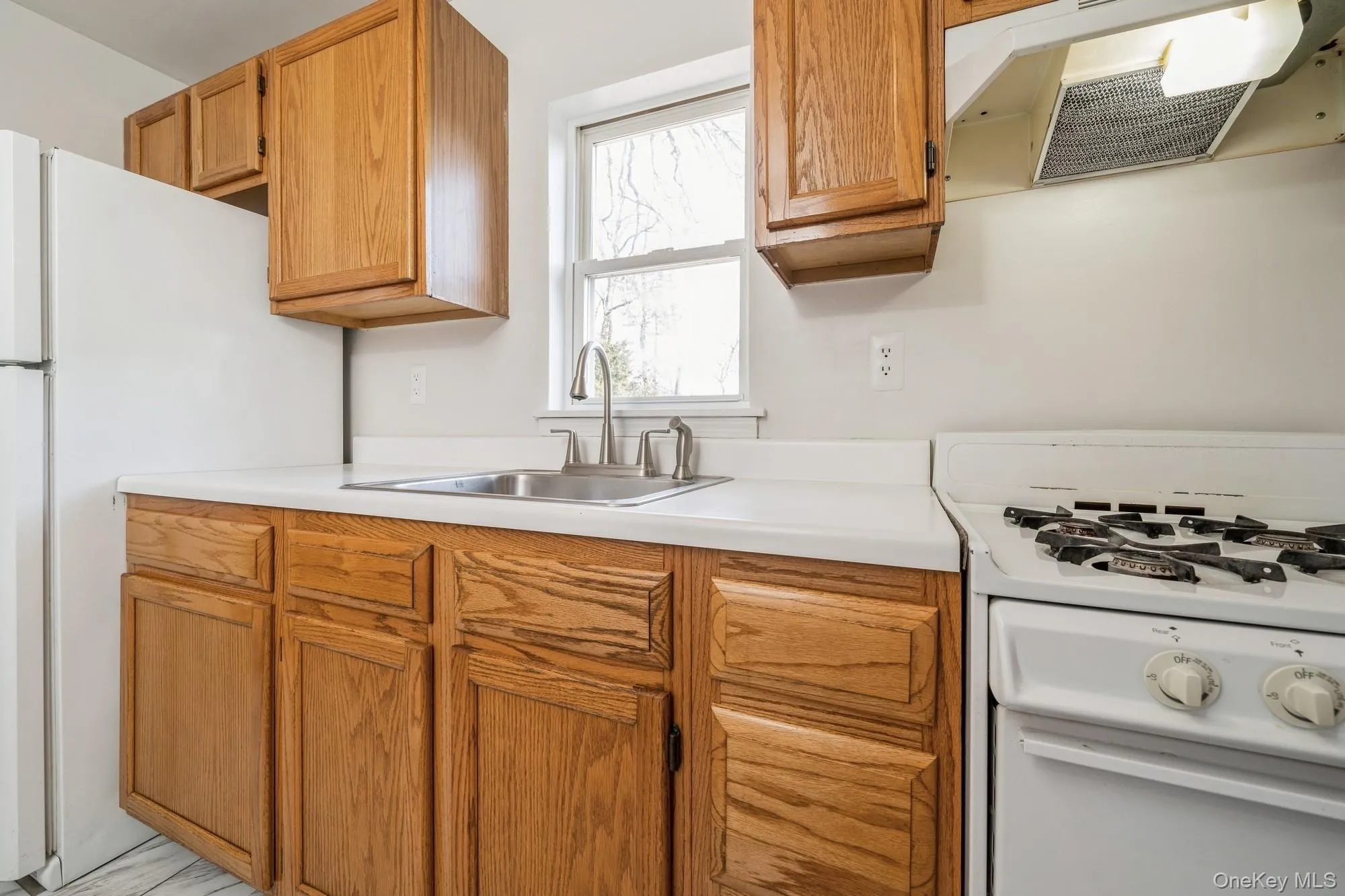 Kitchen featuring white appliances, extractor fan, light countertops, and brown cabinets Kitchen featuring white appliances, extractor fan, light countertops, and brown cabinets