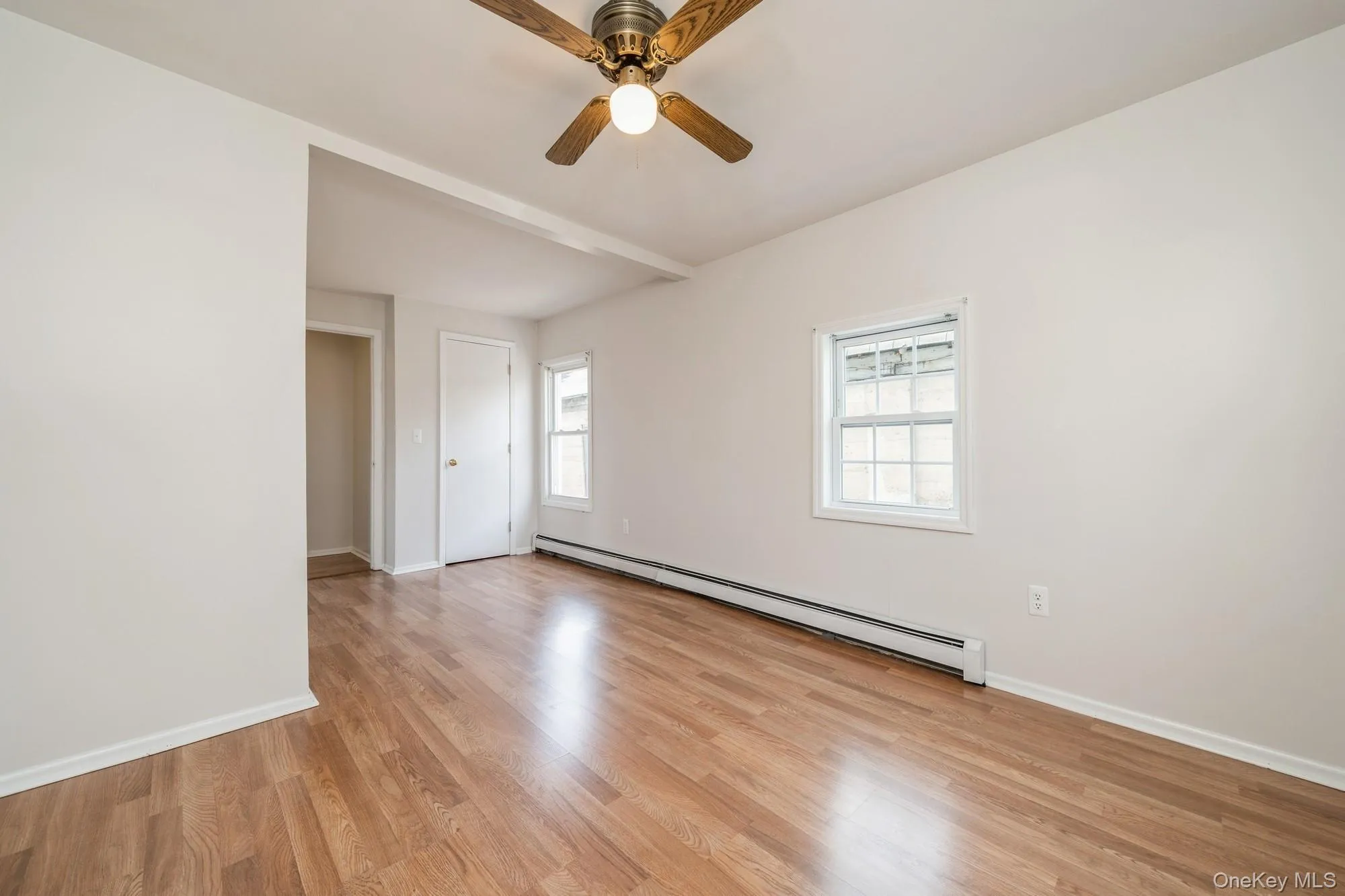 Empty bedroom featuring a baseboard heating unit, light wood-type flooring, and a ceiling fan Empty bedroom featuring a baseboard heating unit, light wood-type flooring, and a ceiling fan