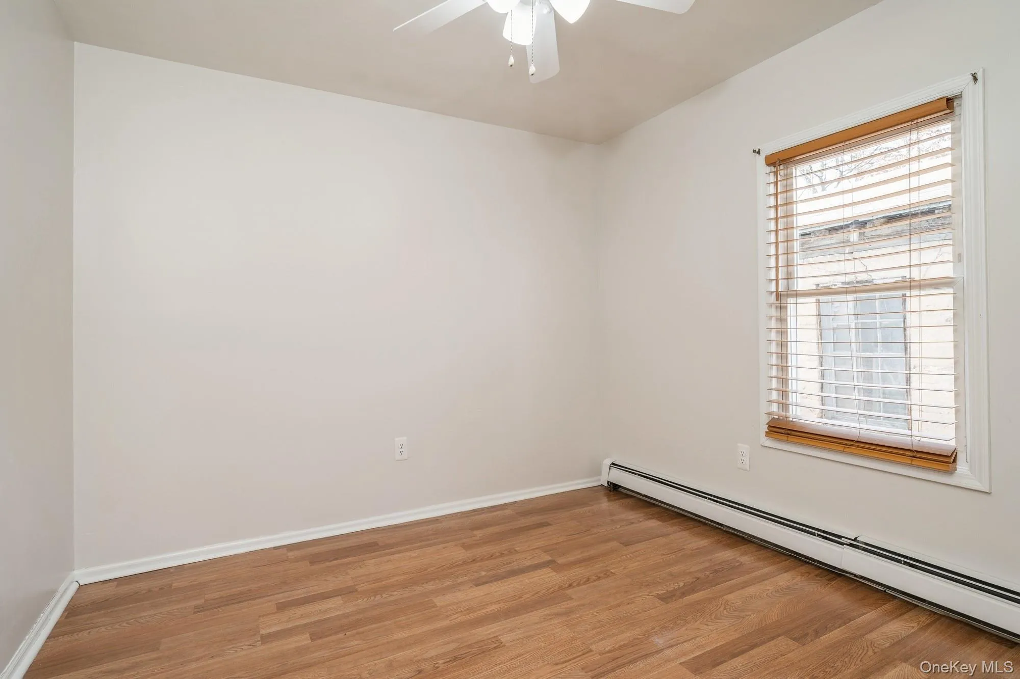 Unfurnished bedroom with light wood-type flooring, a baseboard heating unit, and ceiling fan Unfurnished bedroom with light wood-type flooring, a baseboard heating unit, and ceiling fan