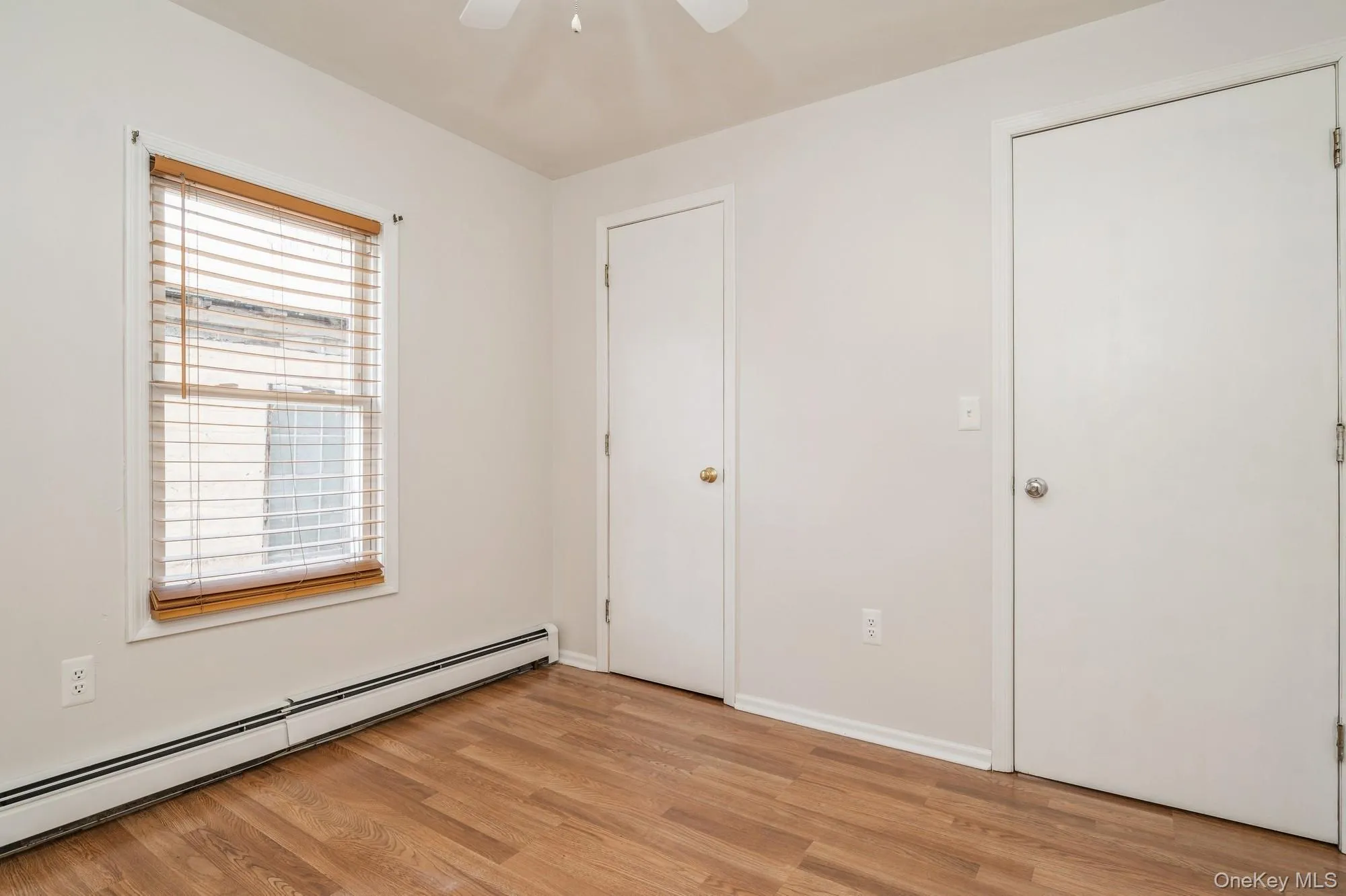 Unfurnished bedroom featuring a baseboard radiator, light wood-type flooring, and ceiling fan Unfurnished bedroom featuring a baseboard radiator, light wood-type flooring, and ceiling fan